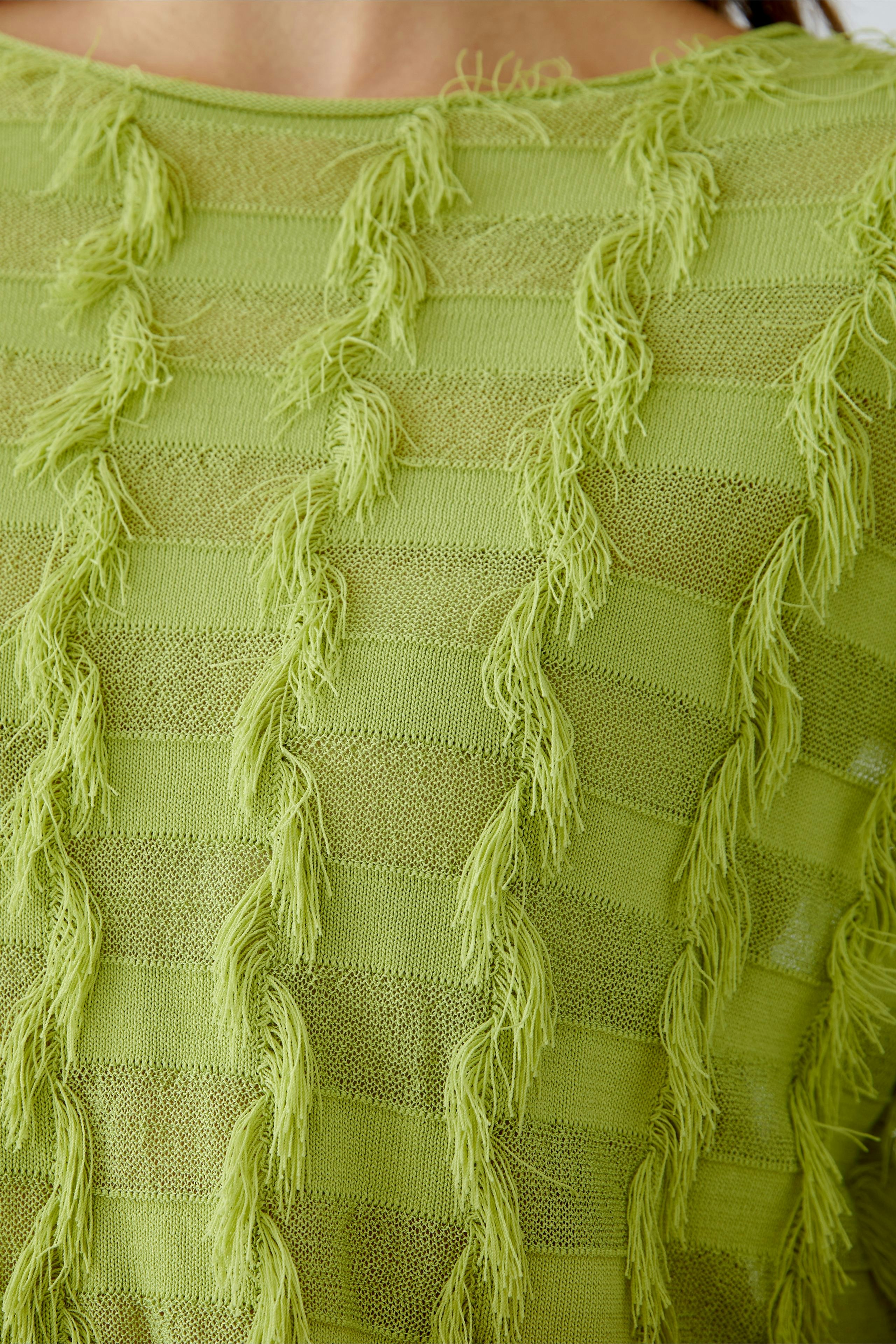 Stylish women's pullover in vibrant green with textured fringes, perfect for a chic look.