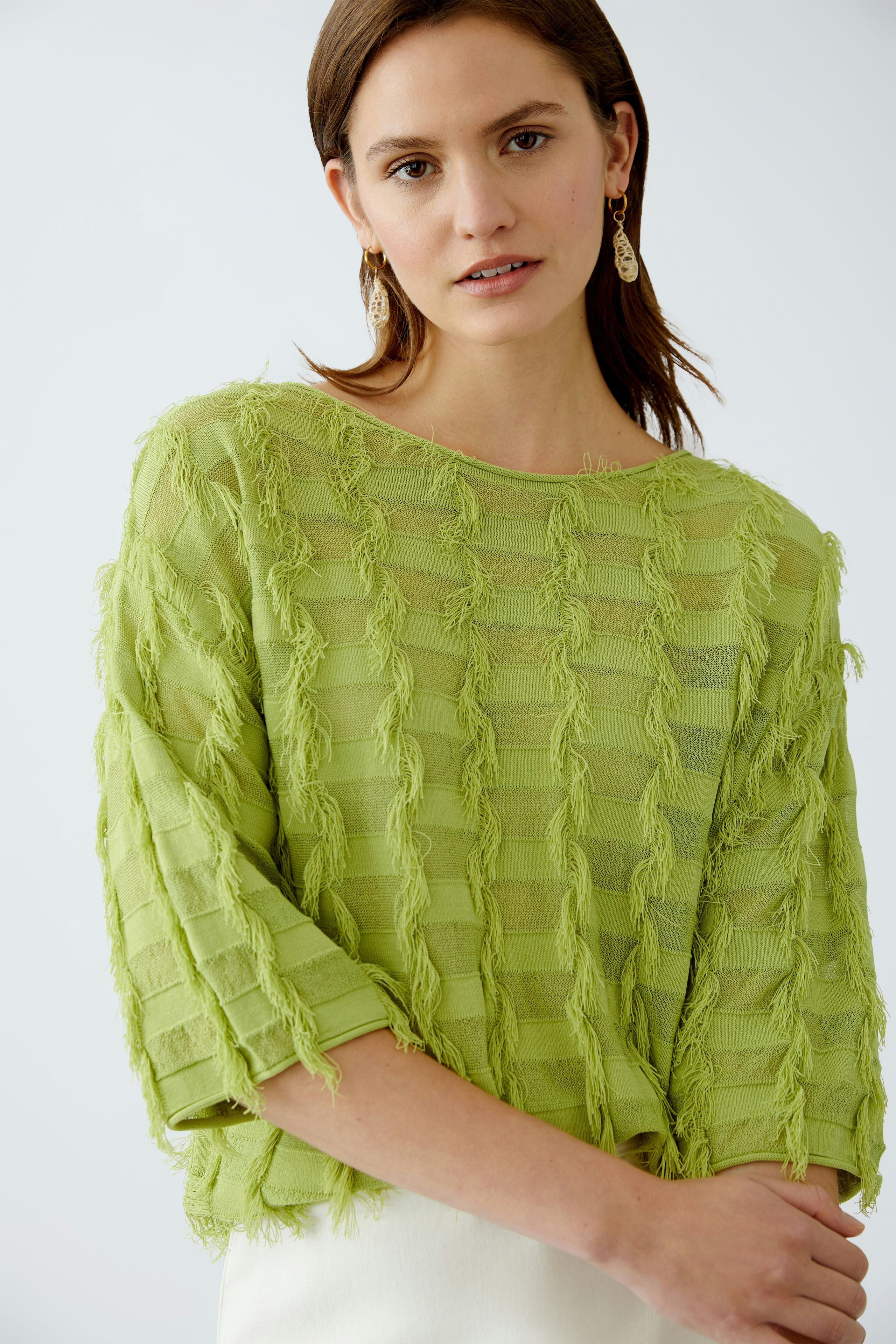 Modern women's pullover: A woman in a light green textured pullover with a relaxed fit.