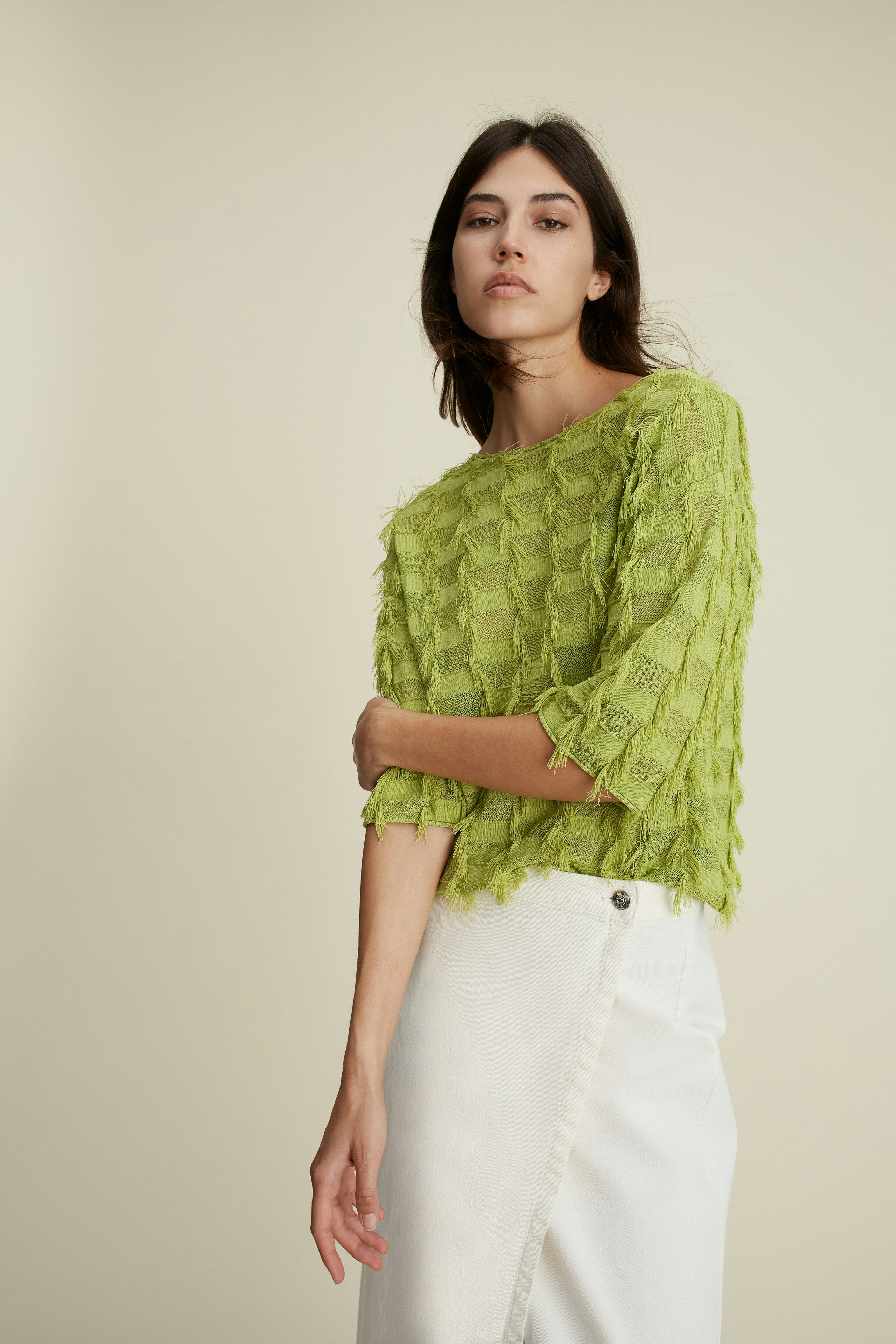 Modern women's pullover: A woman in a textured green pullover with three-quarter sleeves poses elegantly.