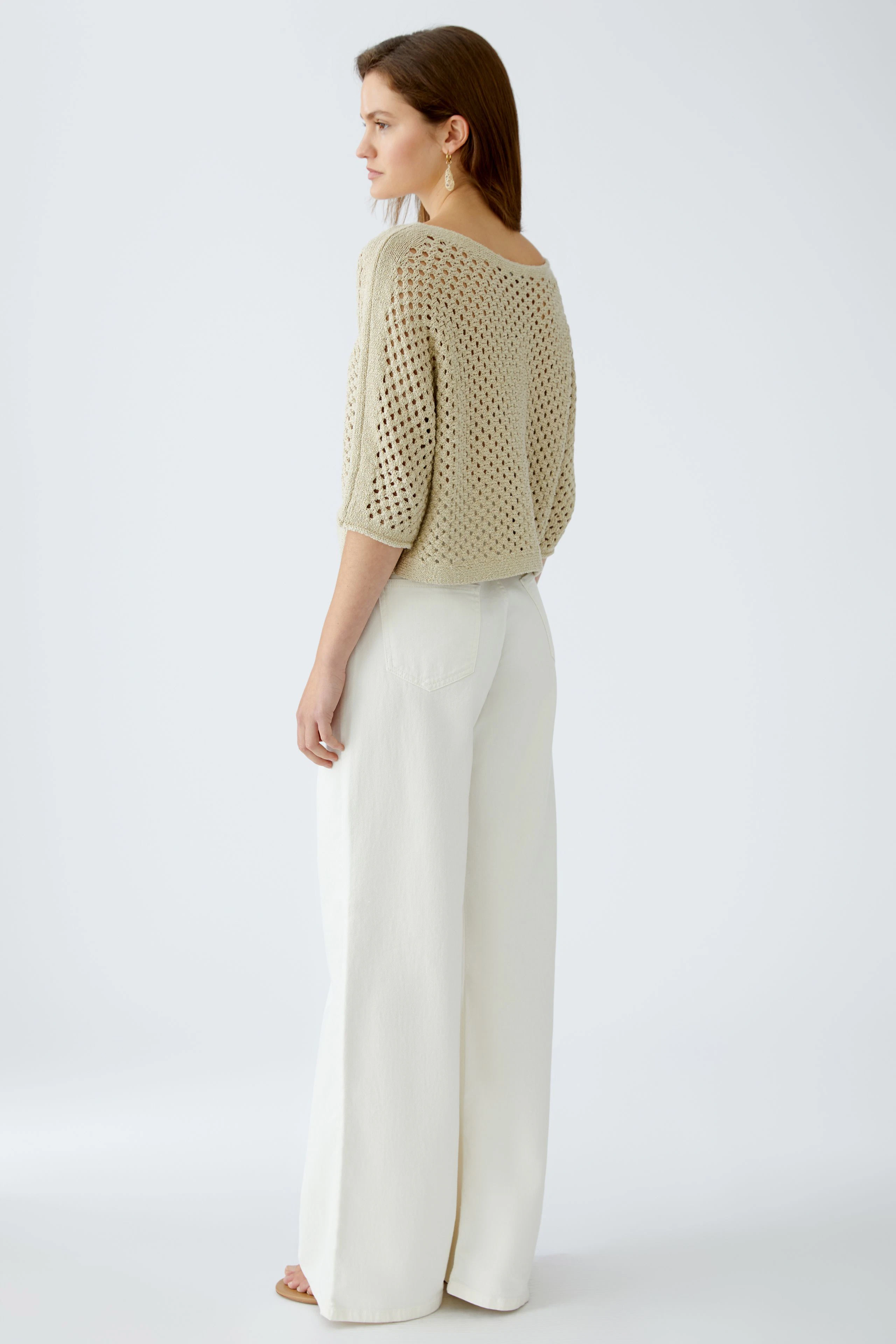 Stylish women's pullover: A woman in a light knit pullover paired with wide-leg pants.