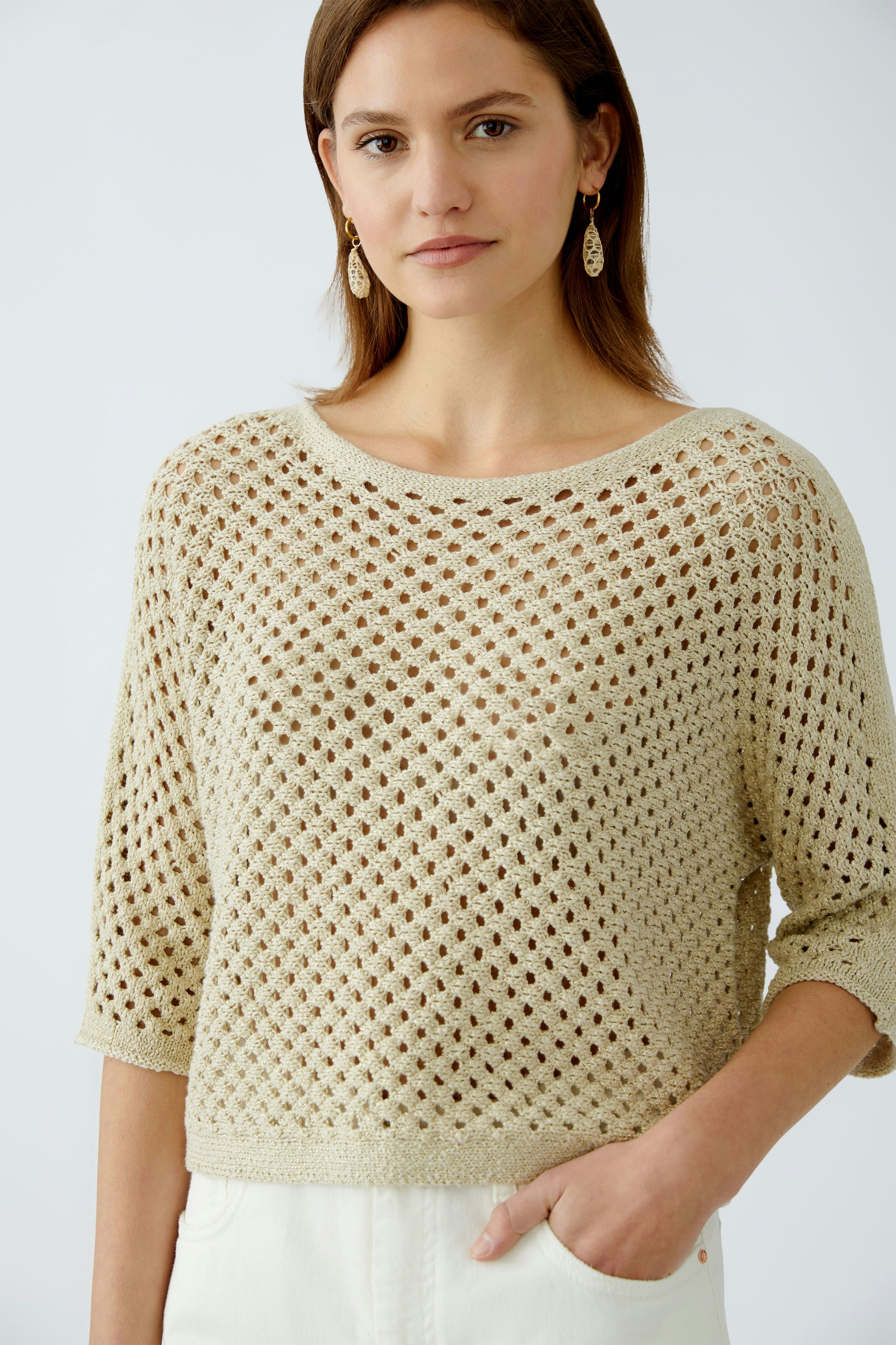 Stylish women's pullover: A woman in a light beige open-knit pullover with three-quarter sleeves.