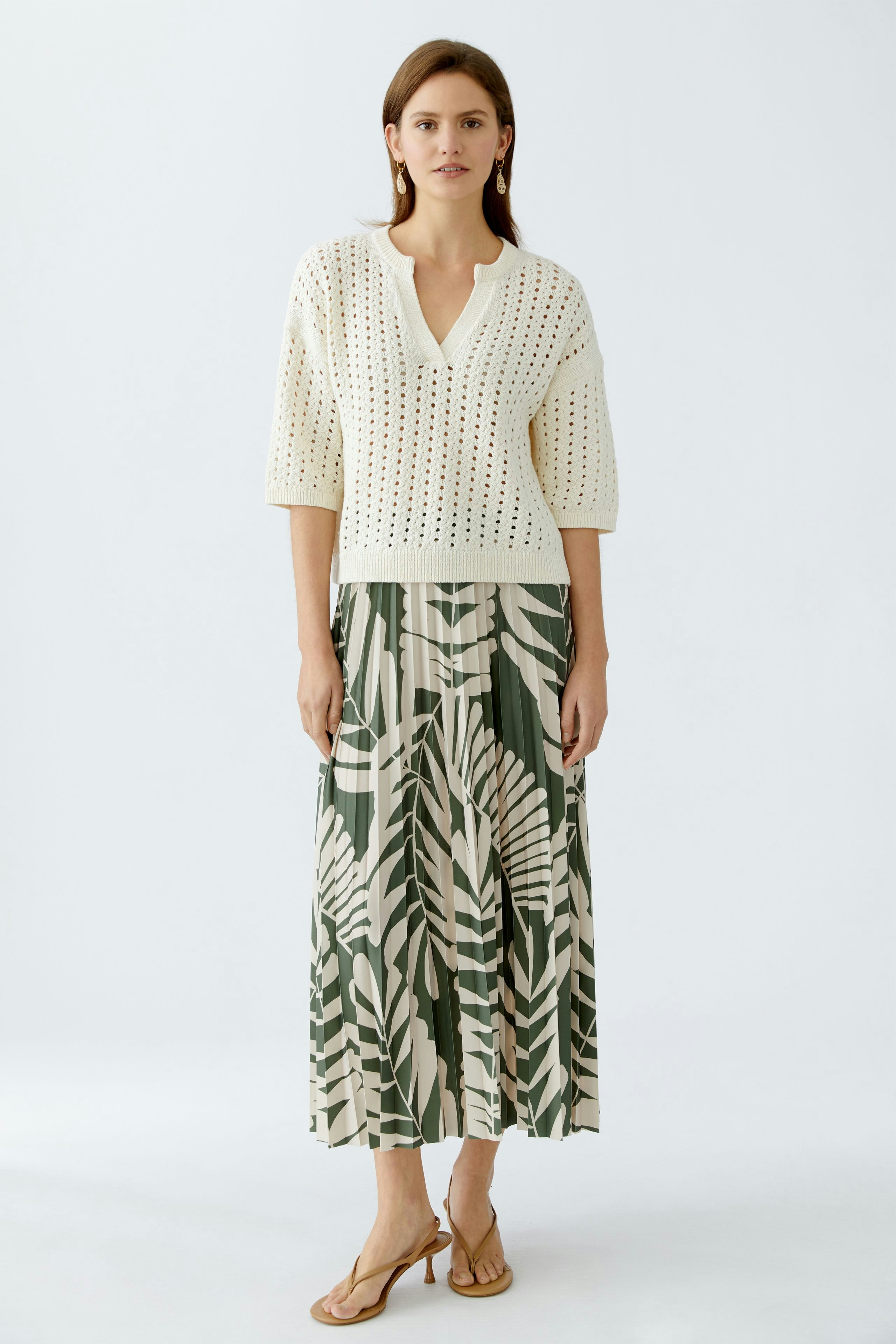 Stylish women's pullover: A woman in a cream-colored, knitted pullover with a V-neck and short sleeves.