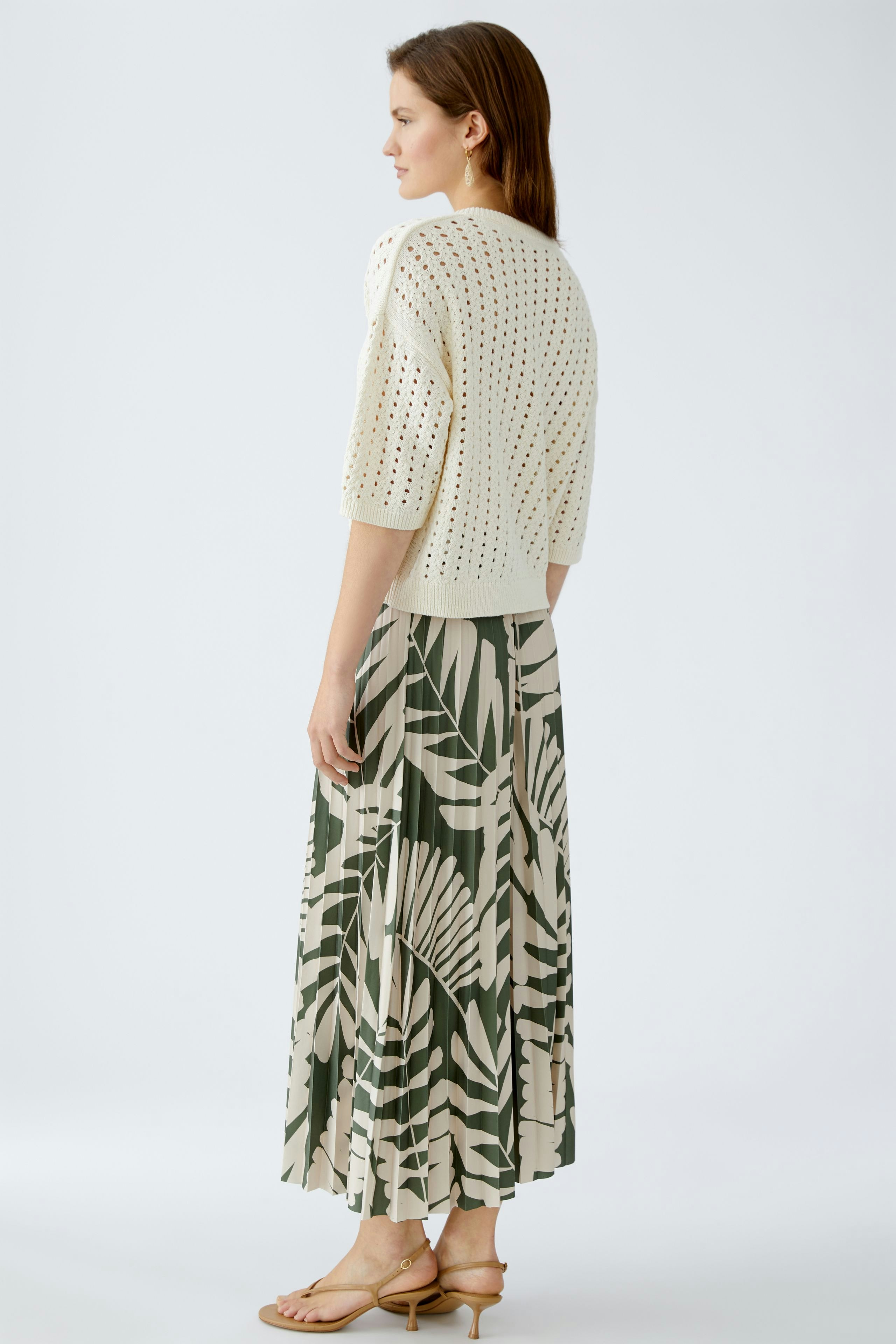 Stylish women's pullover: A woman in a light knit pullover paired with a flowy patterned skirt.