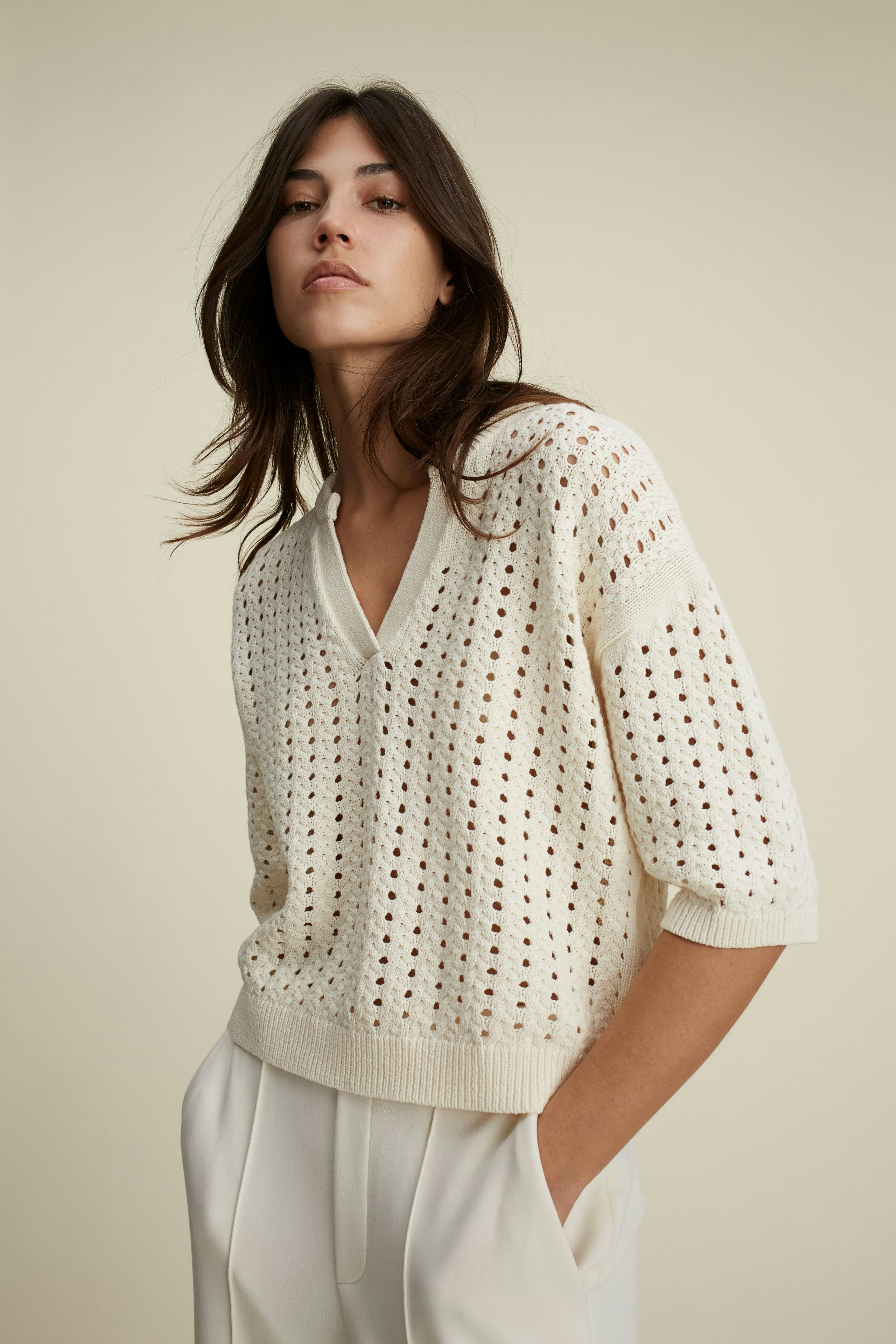 Stylish women's pullover: A woman in a cream open-knit pullover with a relaxed fit.