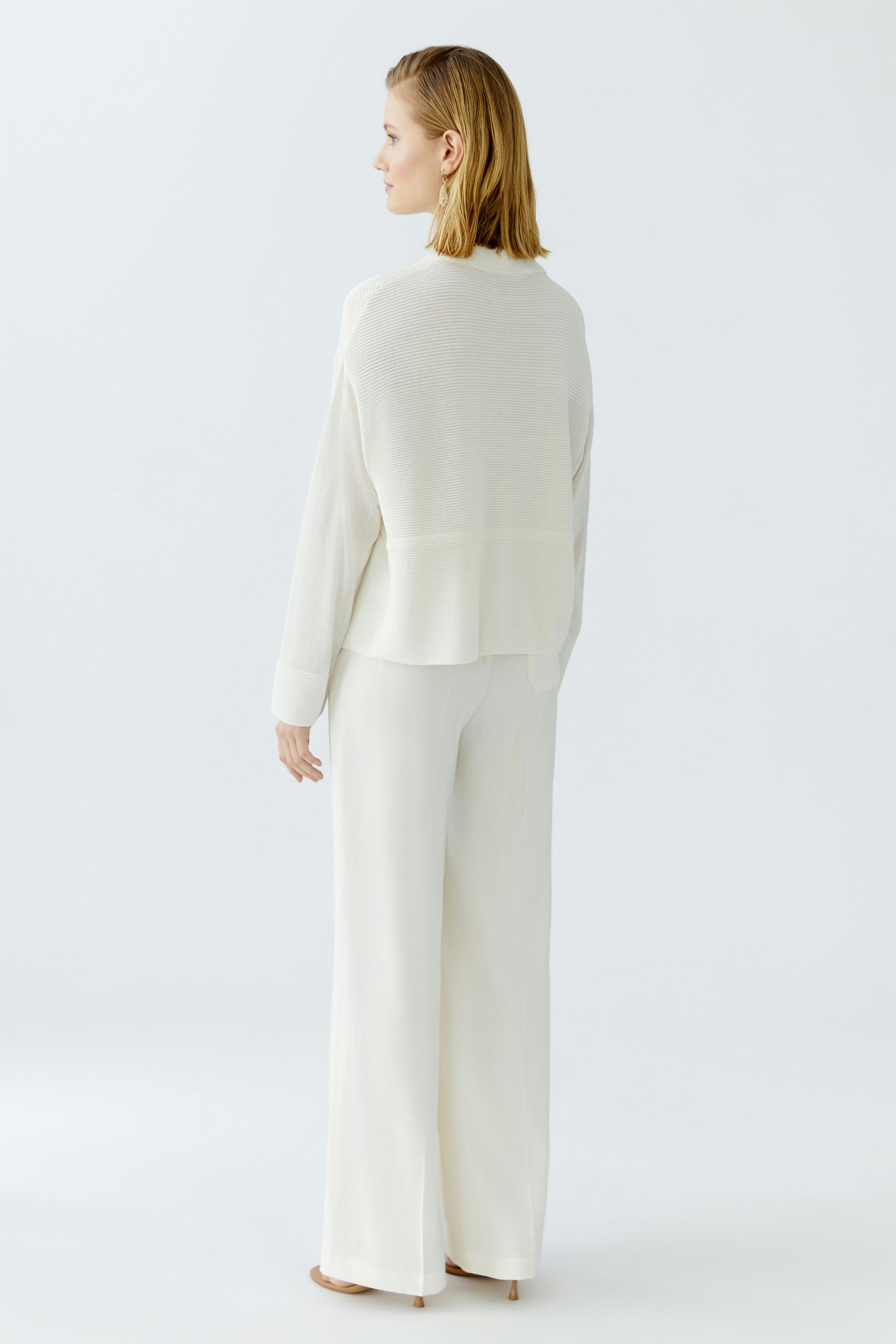Elegant women's cardigan in soft white, styled with wide-leg trousers, showcasing a relaxed fit.