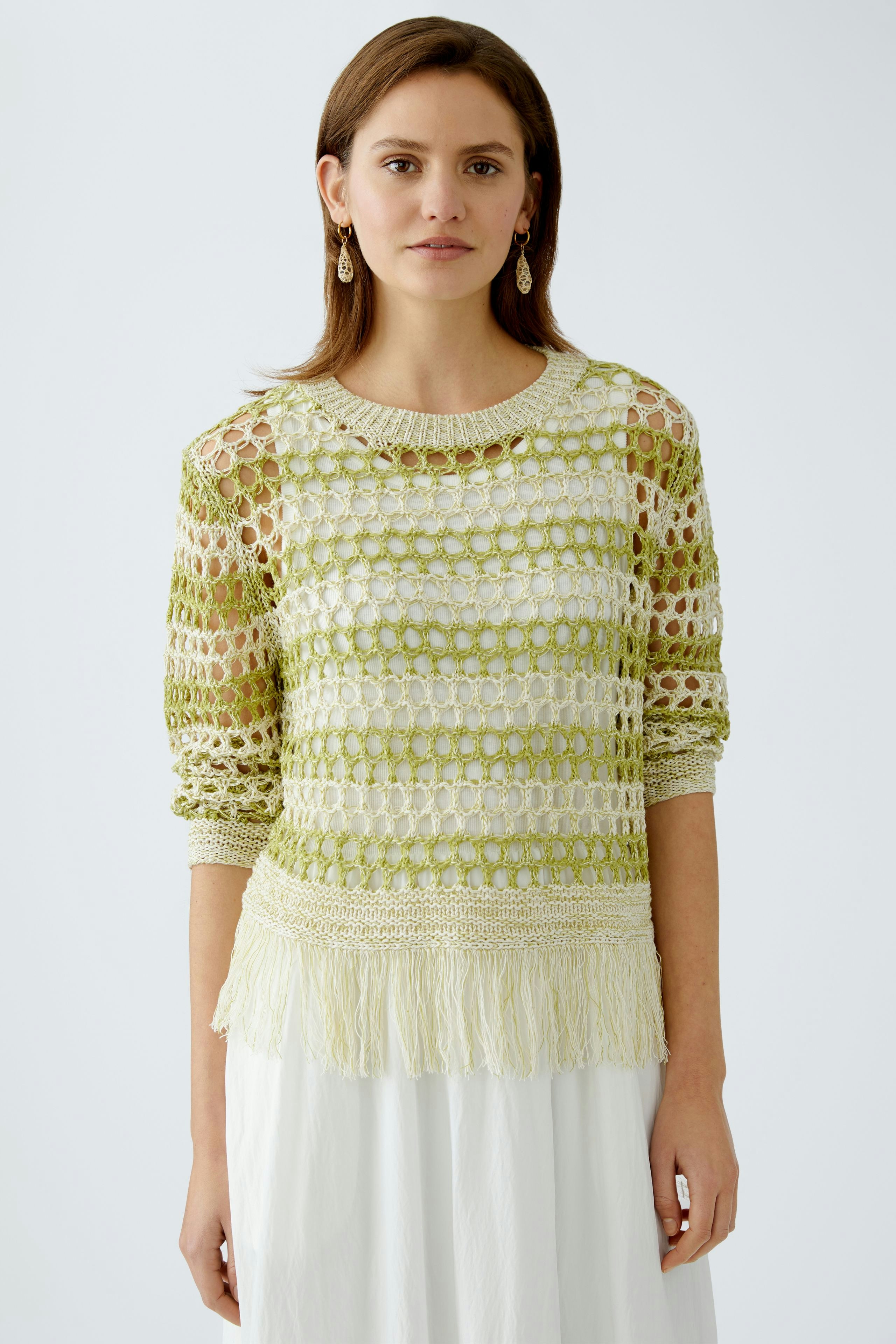 Damen-Pullover: Frau trägt einen hellen, luftigen Strickpullover mit Fransen und transparentem Design.