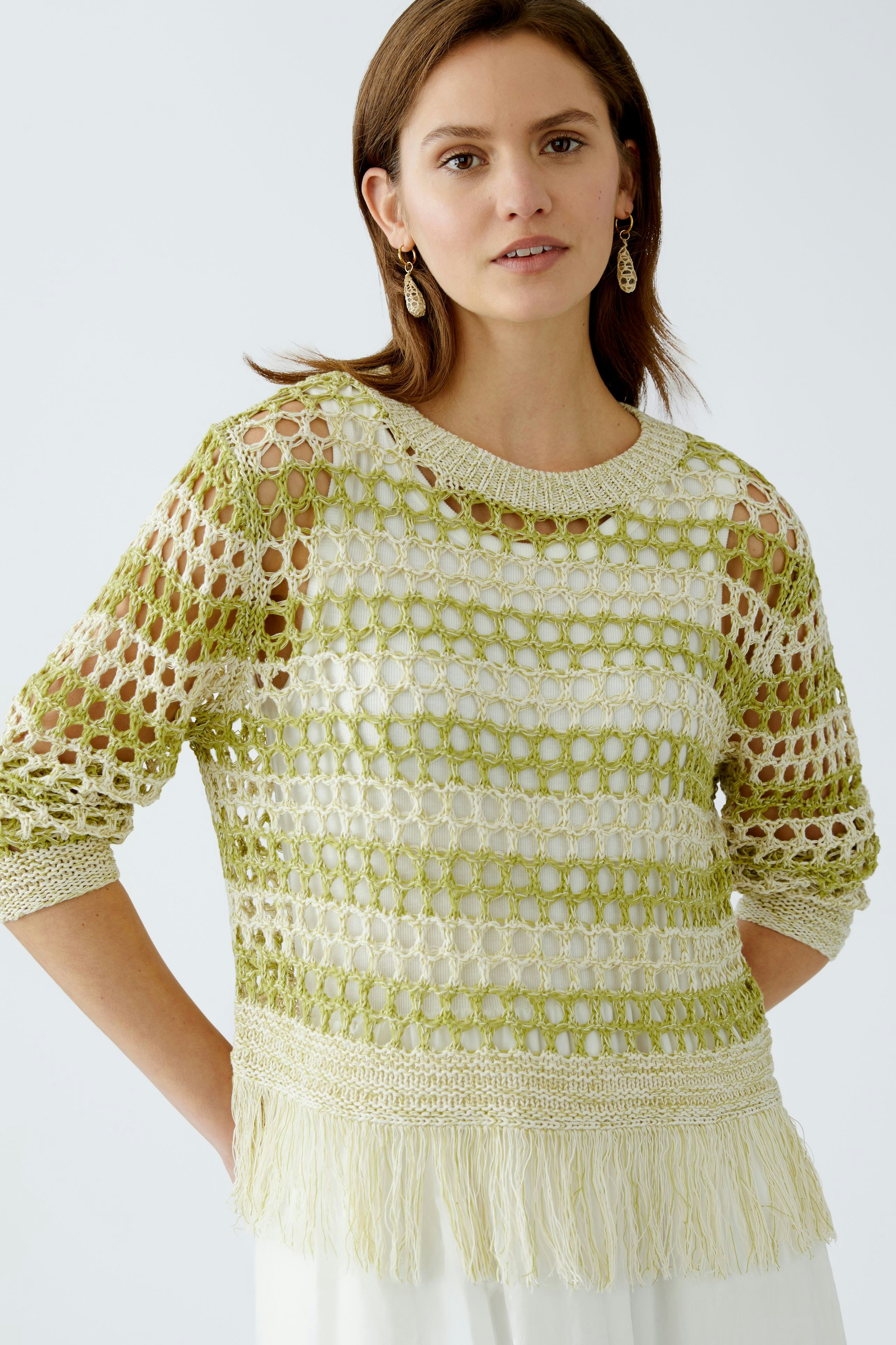 Damen-Pullover: Frau in grünem, luftigen Strickpullover mit Fransen und transparentem Design.