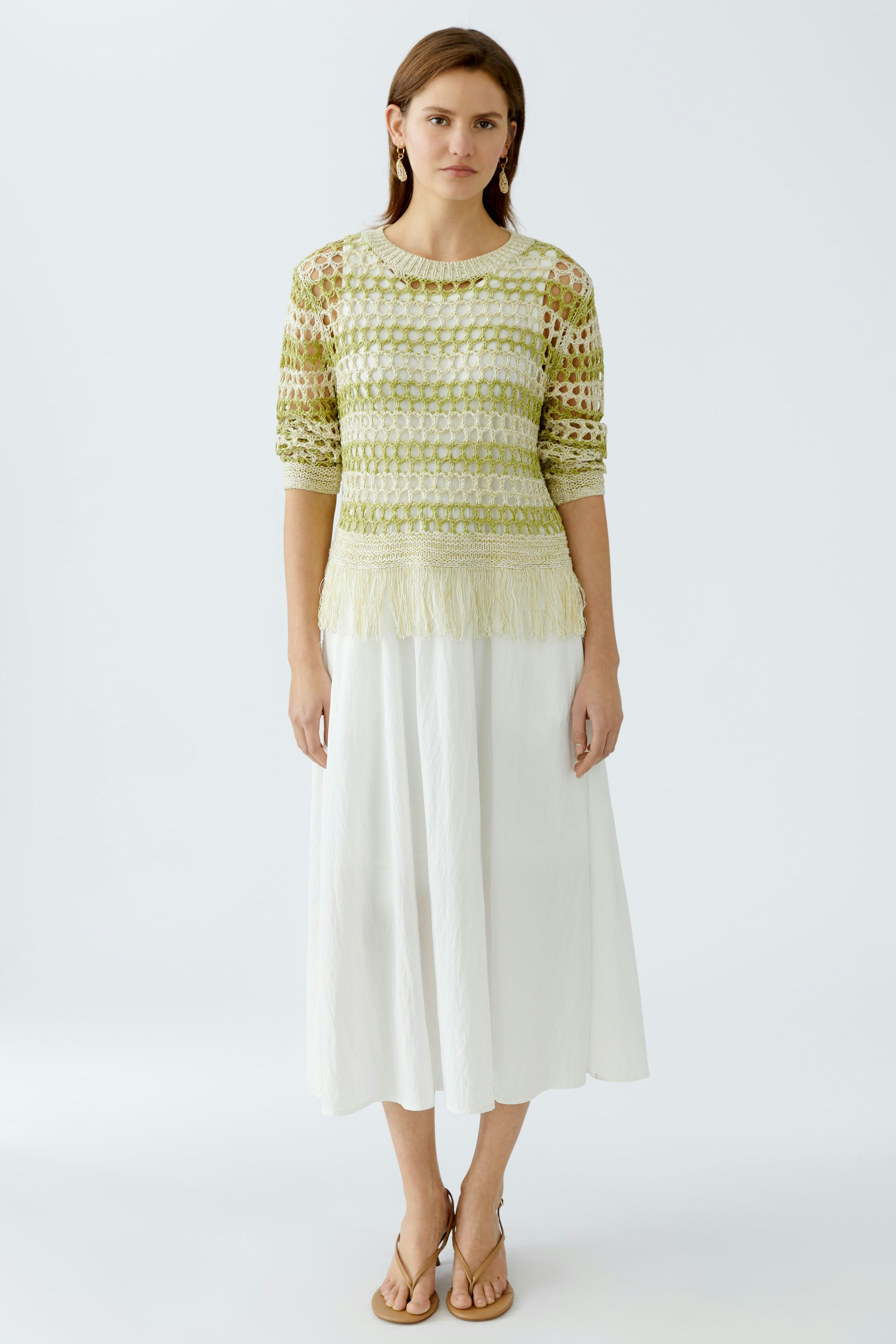 Damen-Pullover: Frau in gelbem, luftigen Strickpullover mit Fransen und weißem Rock.