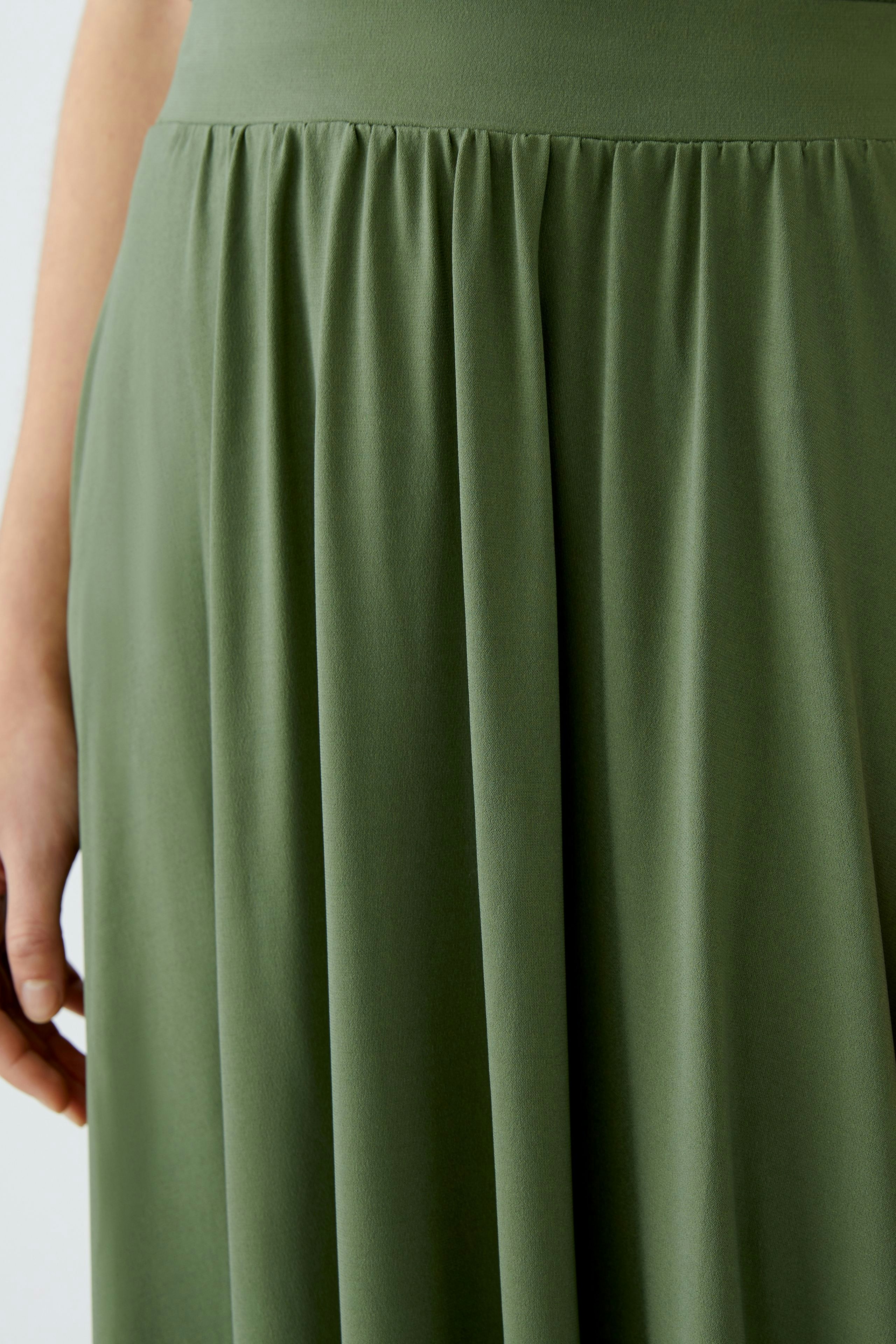 Eleganter A-Linien-Rock: Frau trägt einen fließenden, olivgrünen Rock mit sanften Falten.