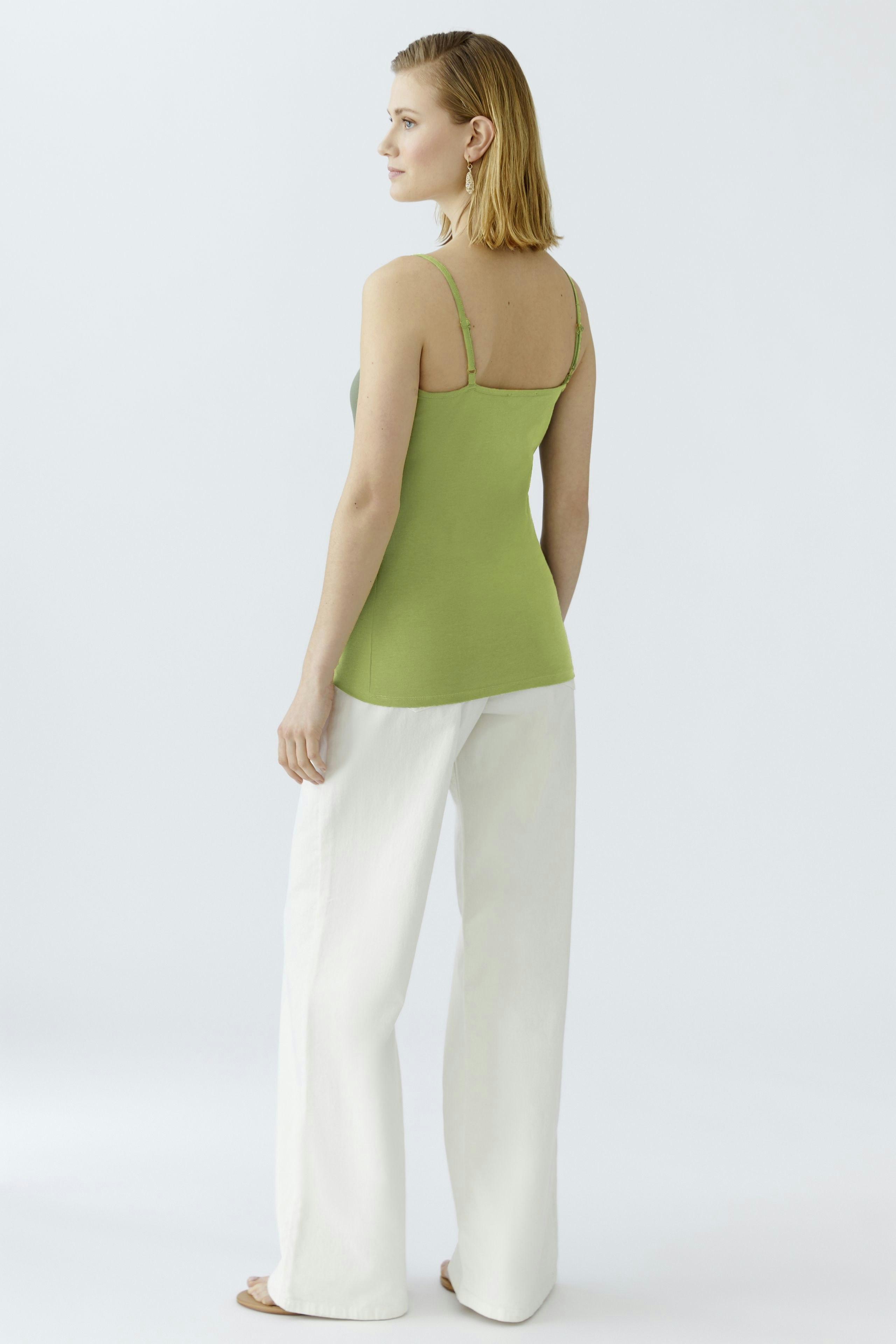 Stylish women's top: A woman in a green tank top paired with white wide-leg pants.
