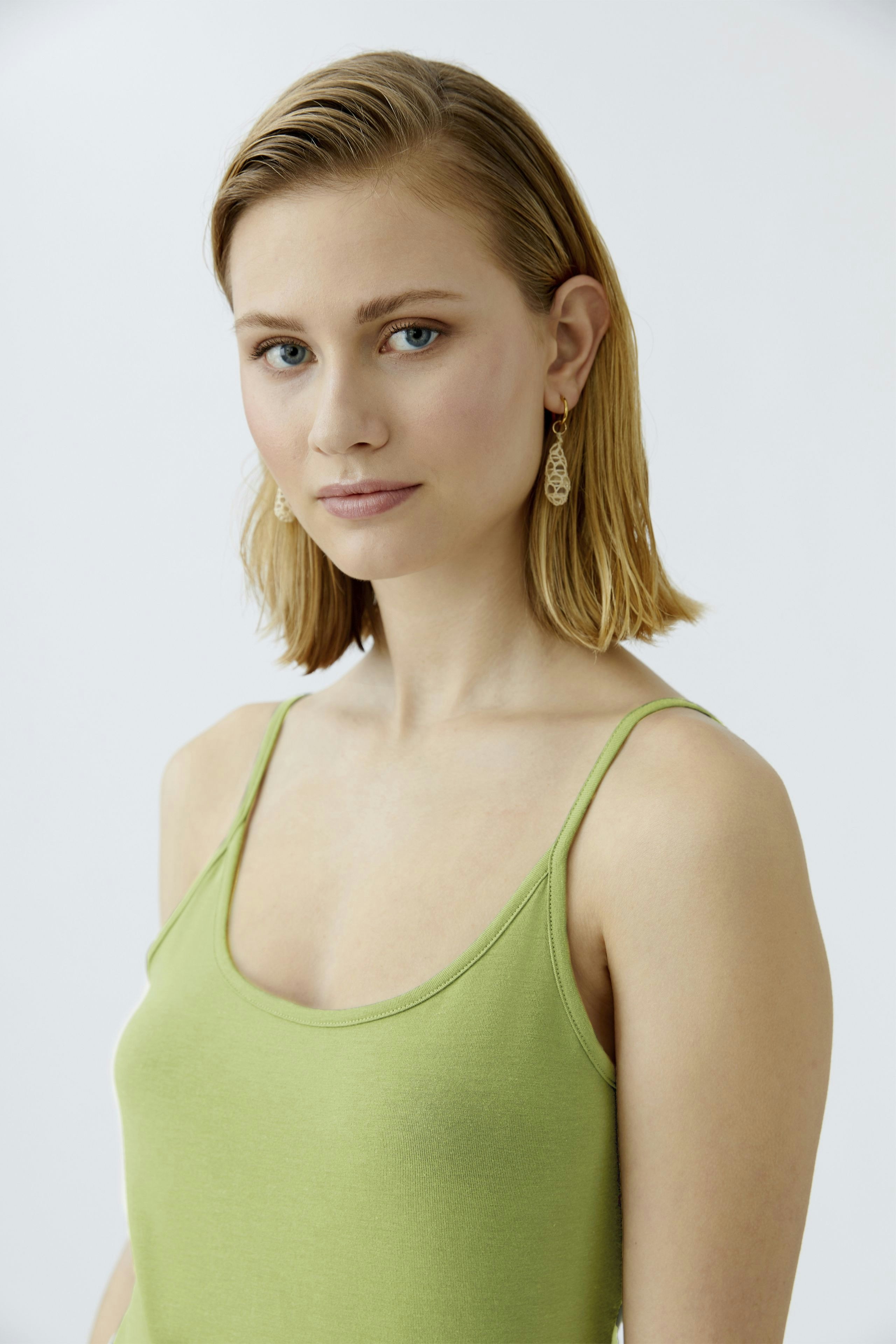 Stylish women's top: A woman in a green tank top, showcasing a fresh and modern look.