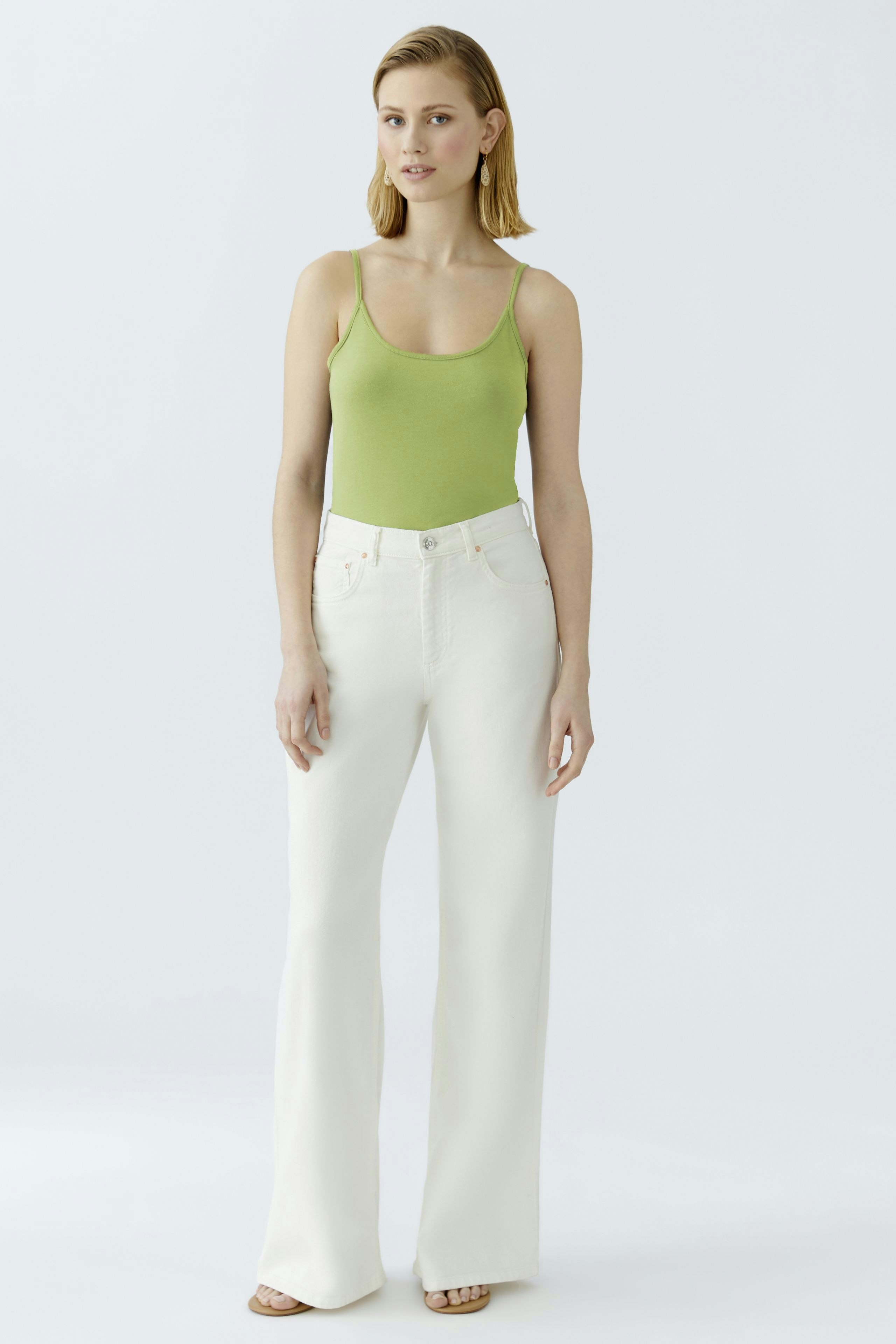 Stylish women's top: A woman in a green tank top paired with white wide-leg pants.
