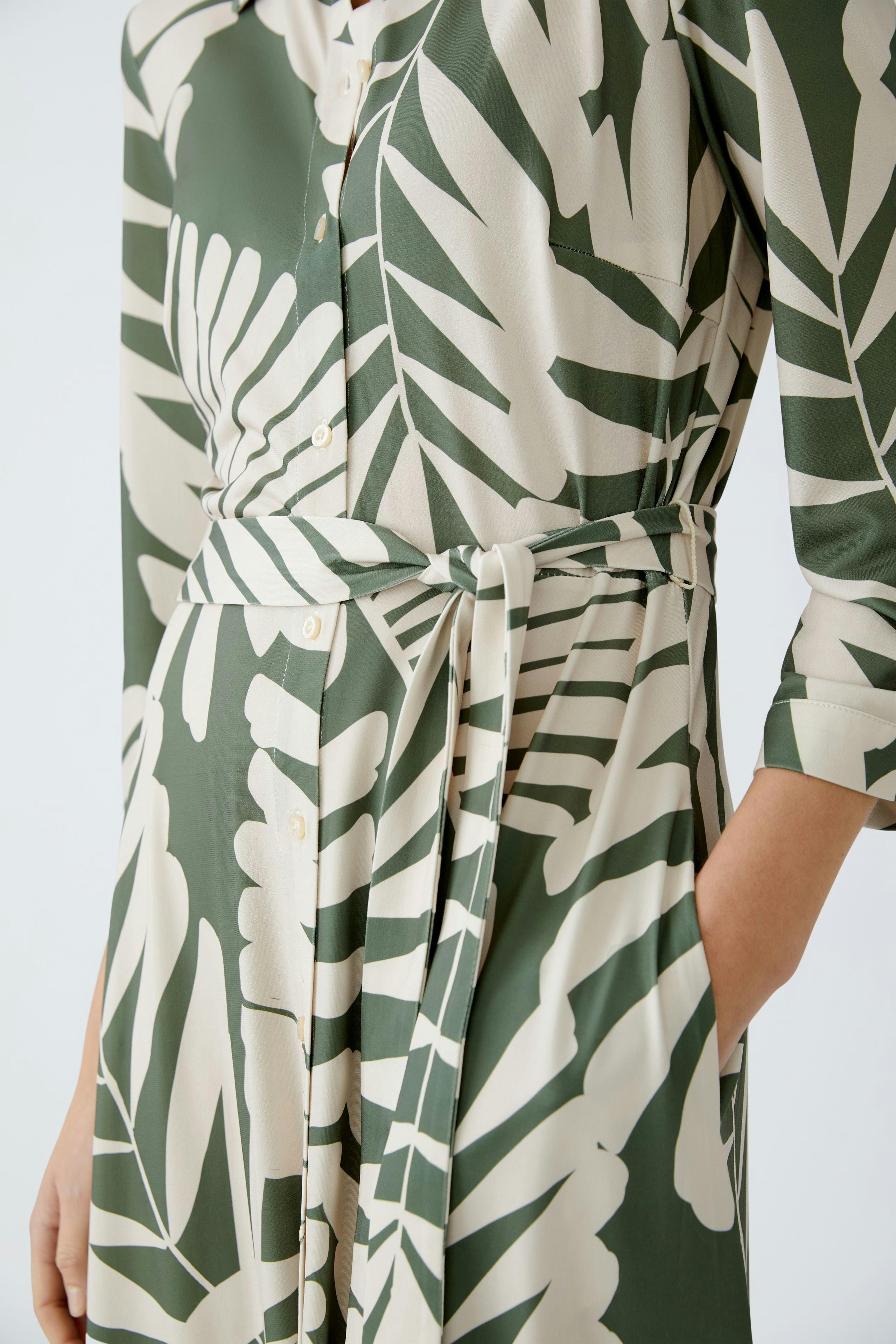 Hemdblusenkleid: Elegante Frau in einem blumigen Kleid mit Gürtel und langen Ärmeln.