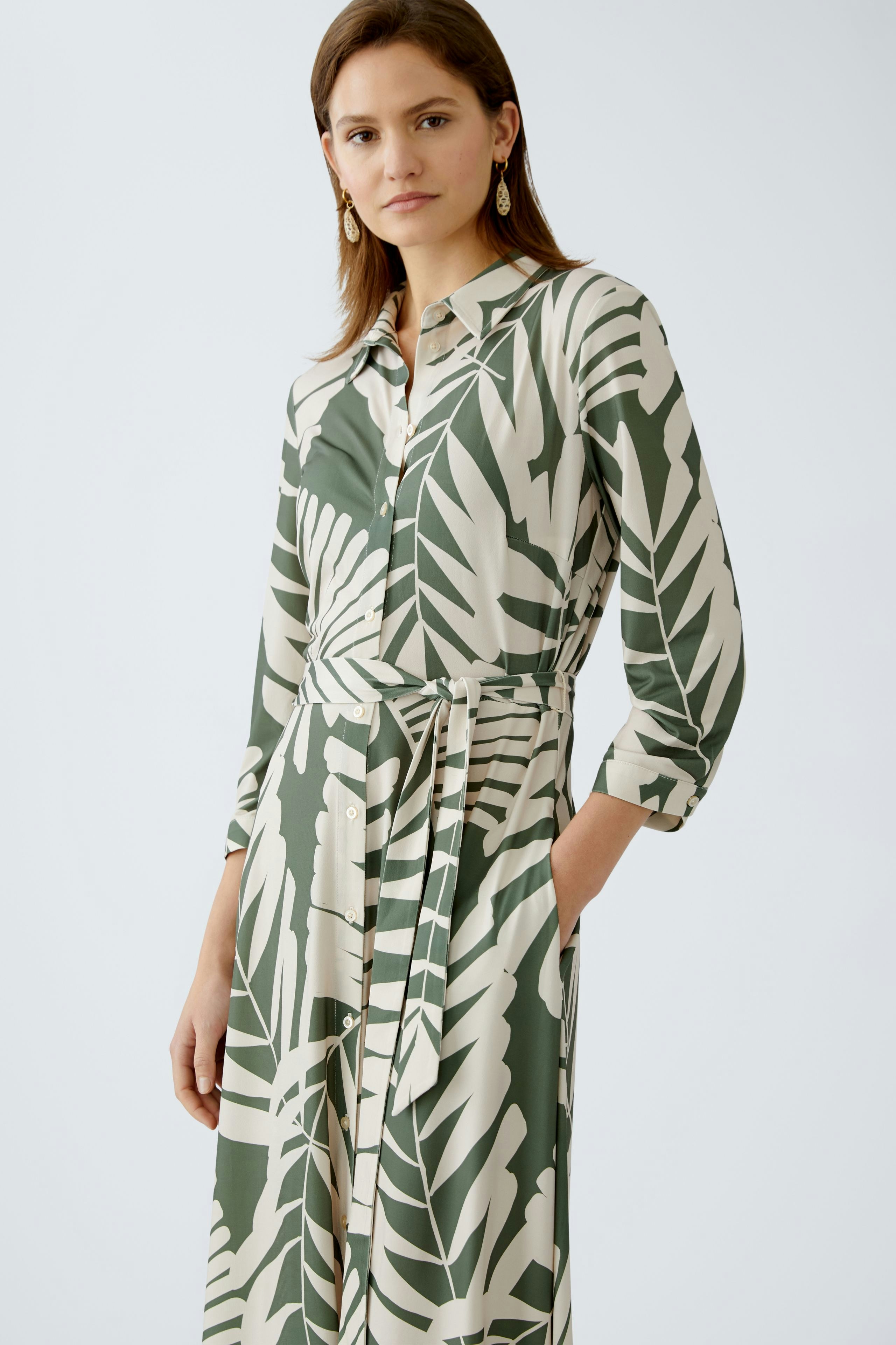 Elegantes Hemdblusenkleid: Frau in einem blumigen Kleid mit Gürtel und langen Ärmeln.