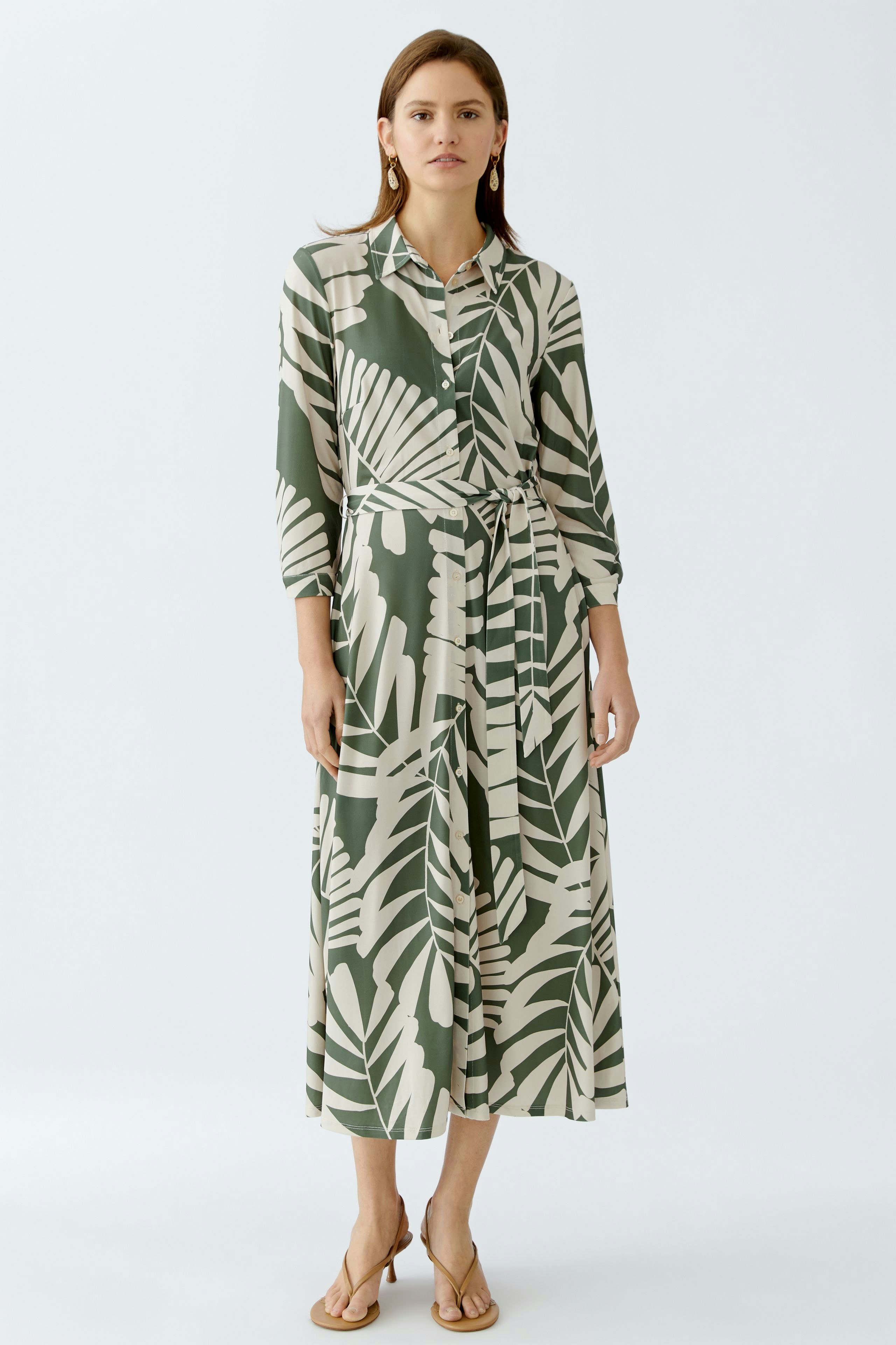 Hemdblusenkleid: Frau in einem eleganten, gemusterten Kleid mit Gürtel und langen Ärmeln.