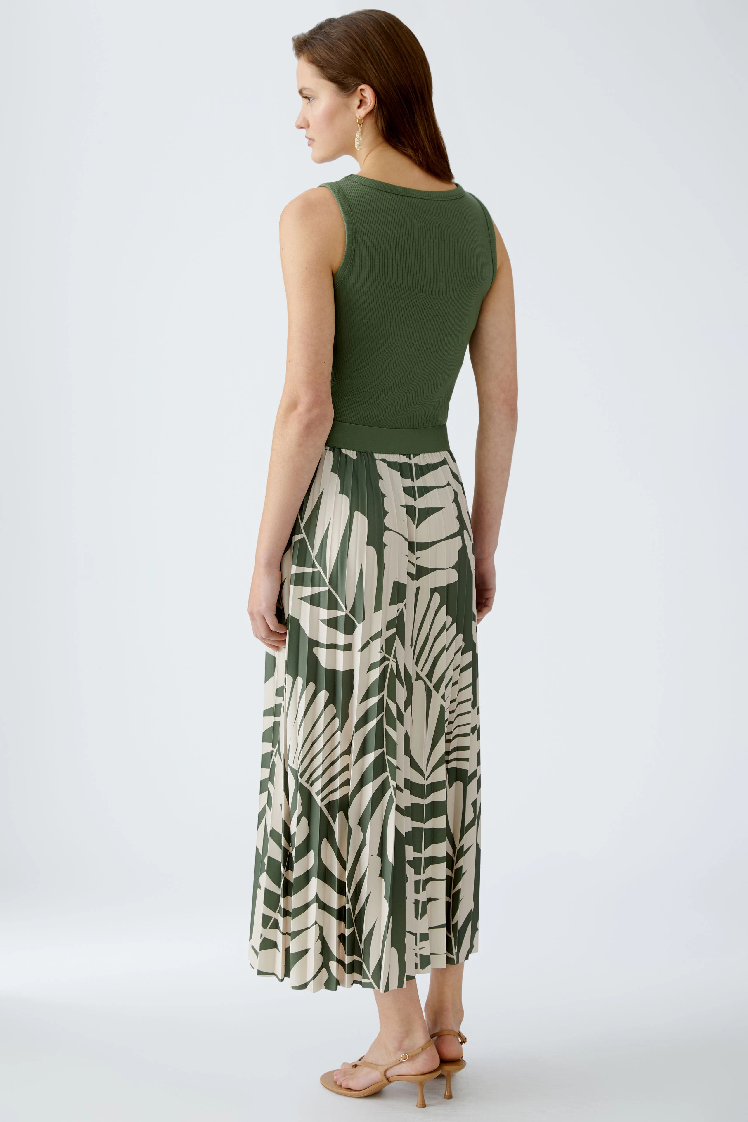 Eleganter Plisseerock: Frau in grünem Plisseerock mit floralem Muster, ideal für sommerliche Anlässe.