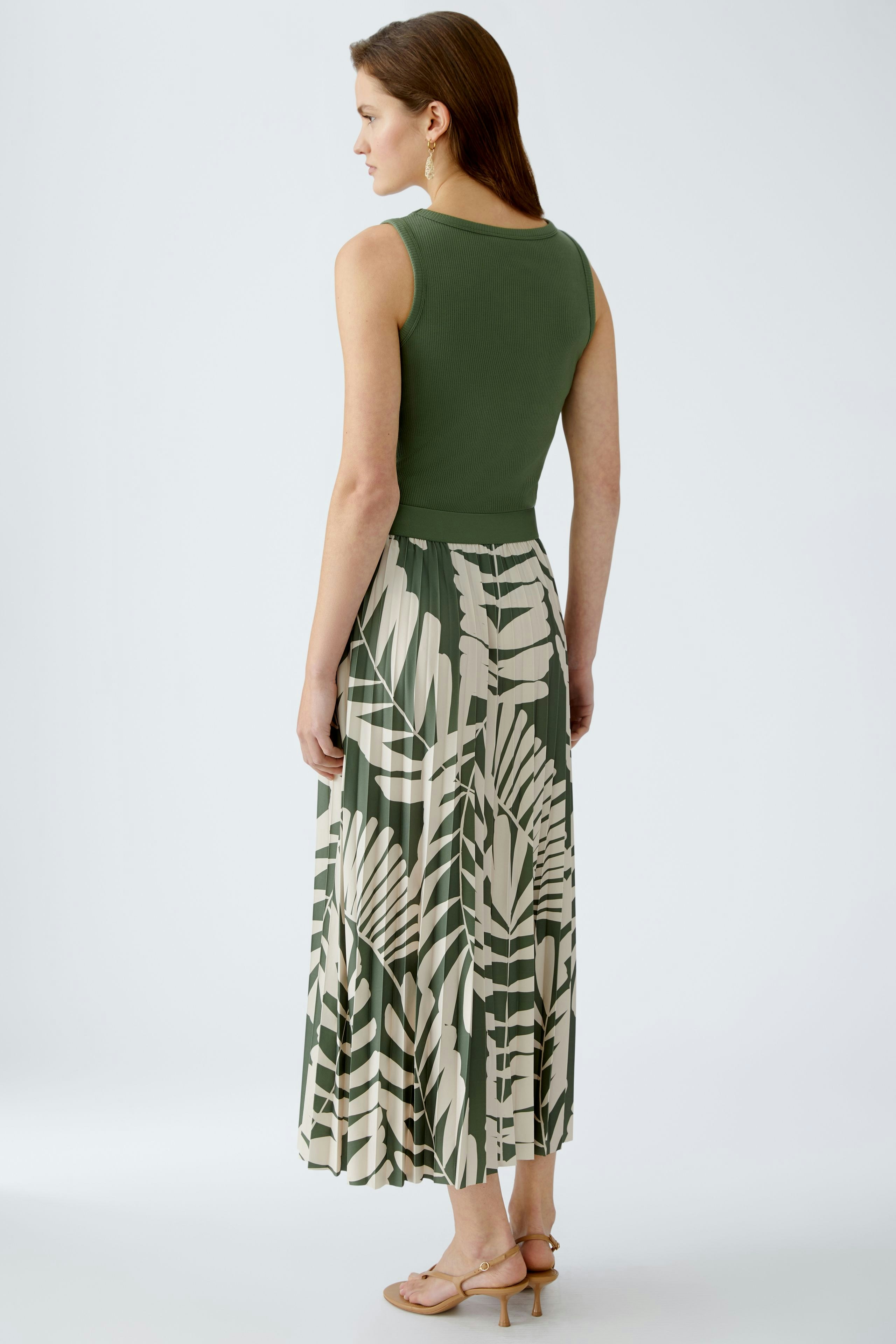 Eleganter Plisseerock: Frau in grünem Plisseerock mit floralem Muster, ideal für sommerliche Anlässe.