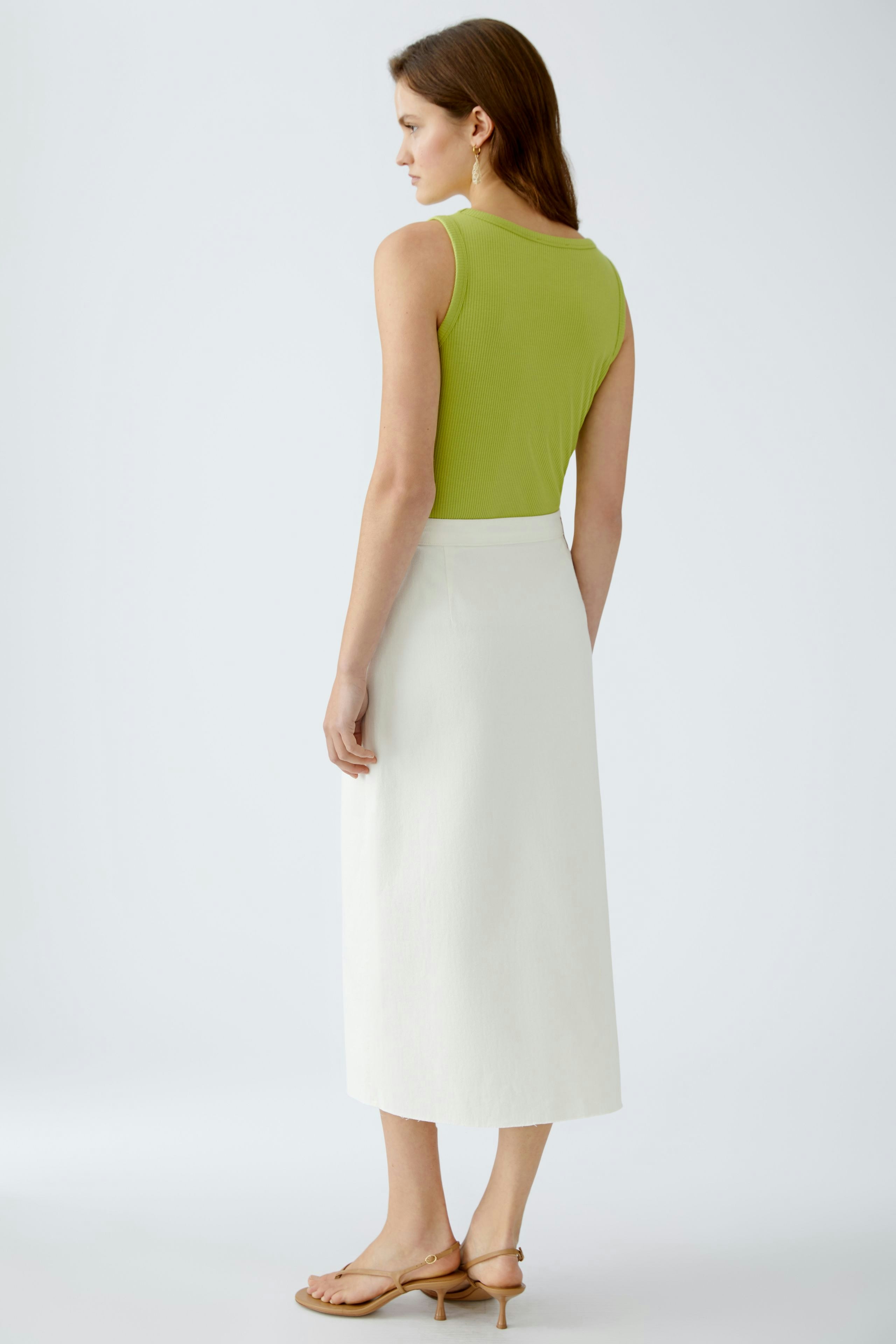 Eleganter Wickelrock: Frau in weißem, knielangem Rock mit schlichter Silhouette und lässigem Oberteil.