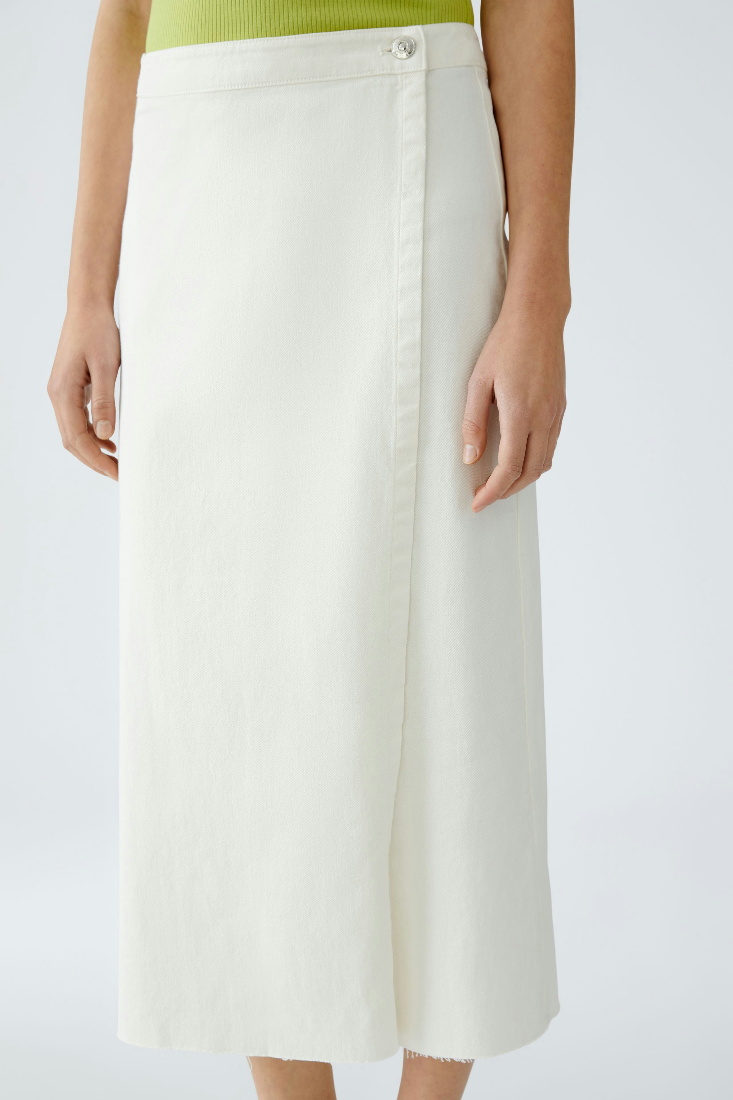 Eleganter Wickelrock: Frau trägt einen weißen Wickelrock mit Knopfdetails und lässigem Oberteil.