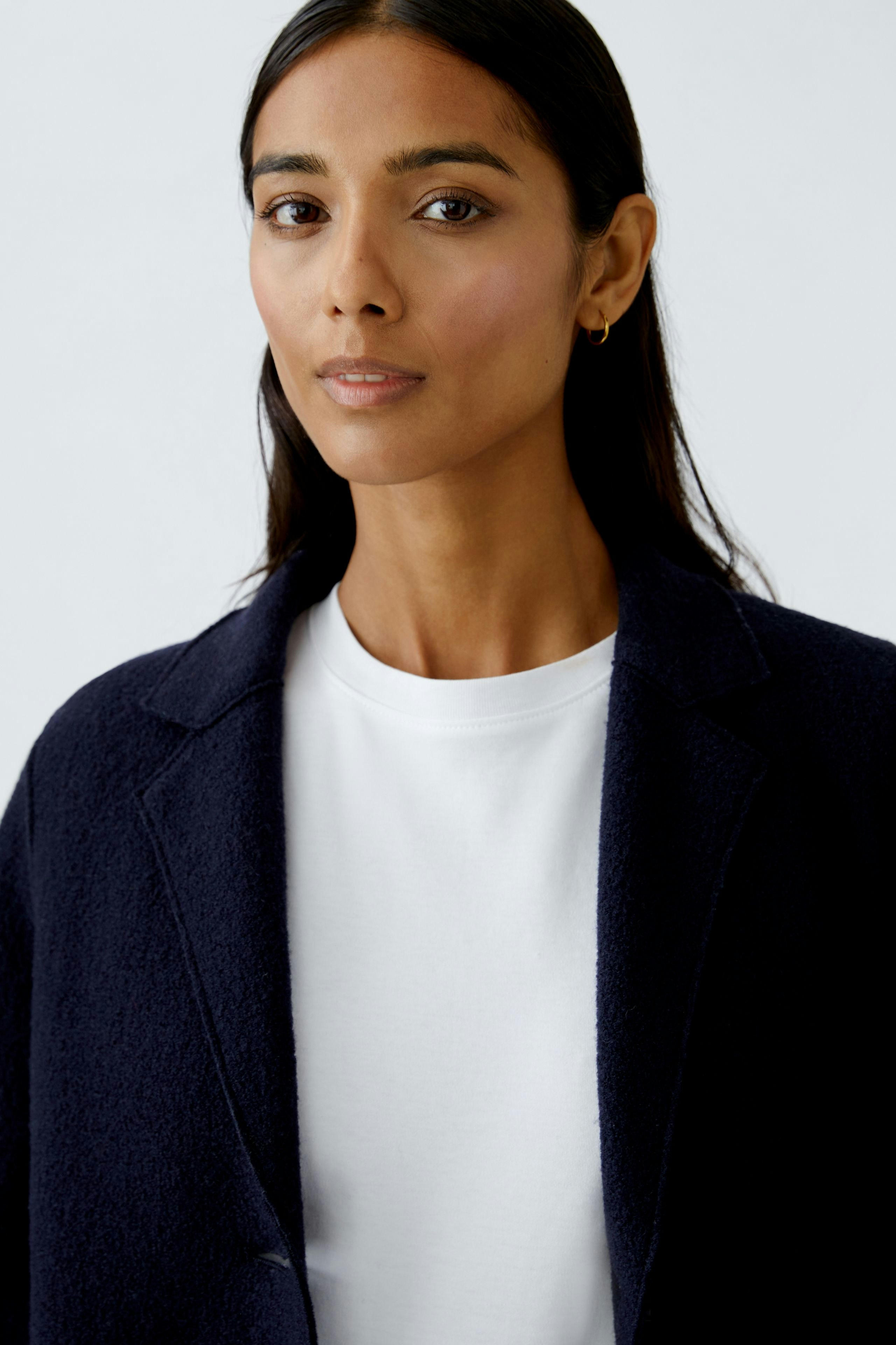 Eleganter Wollmantel: Frau trägt einen dunkelblauen Wollmantel über einem weißen Oberteil und Jeans.