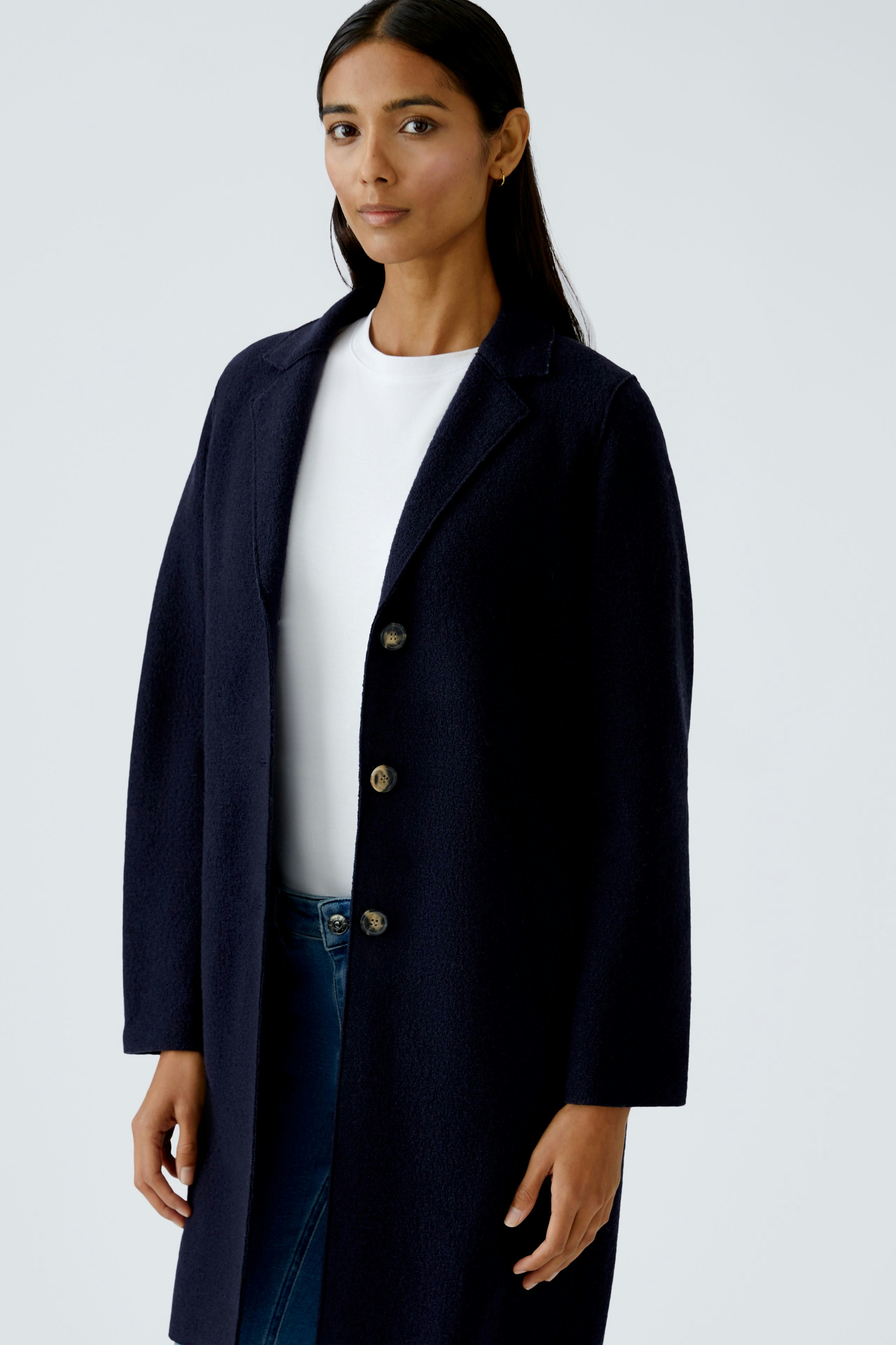 Eleganter Wollmantel: Frau in einem dunkelblauen, langen Wollmantel mit Knöpfen.