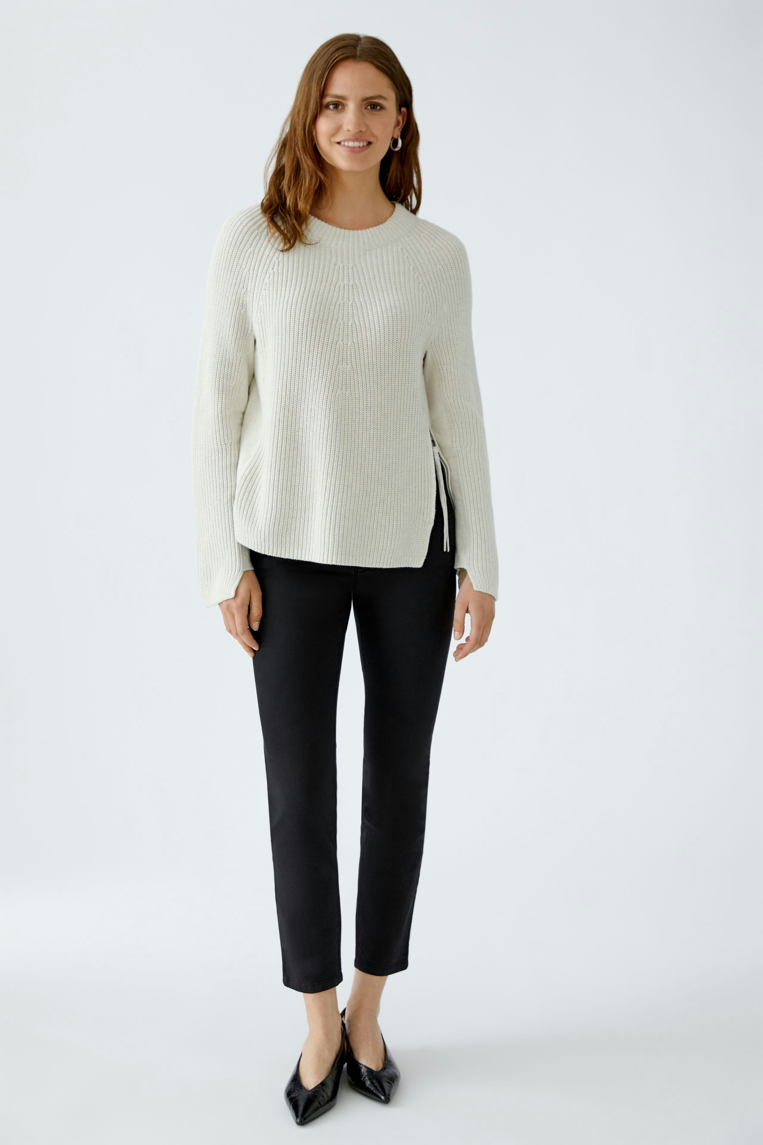 Damen-Pullover: Frau in hellem, strukturiertem Pullover mit lässigem Schnitt und schwarzen Leggings.