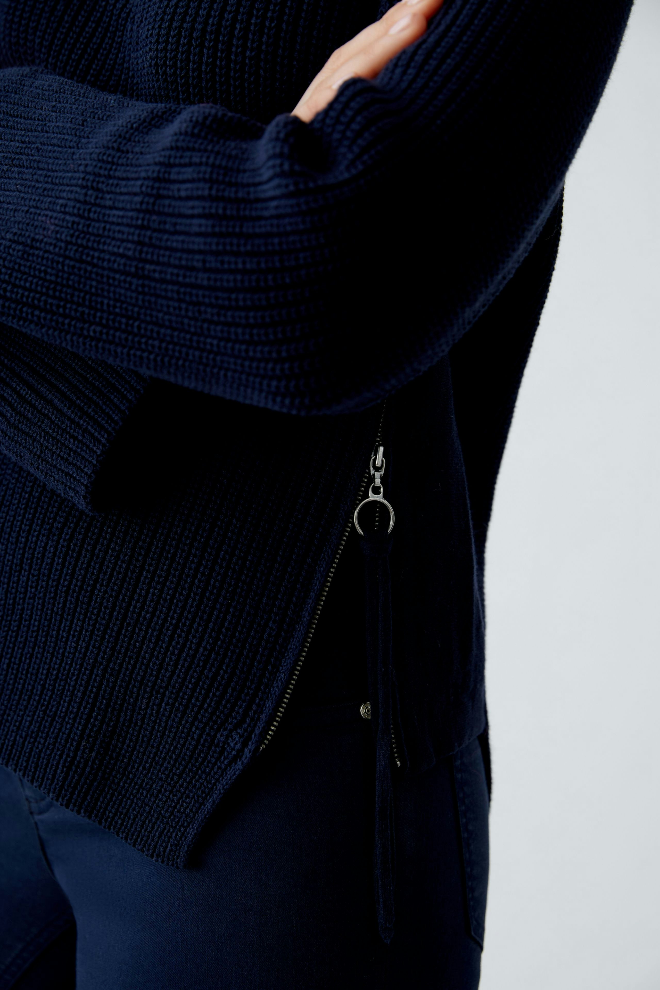 Damen-Pullover: Frau in navy-blauem Strickpullover mit seitlichem Reißverschluss und lässigem Look.