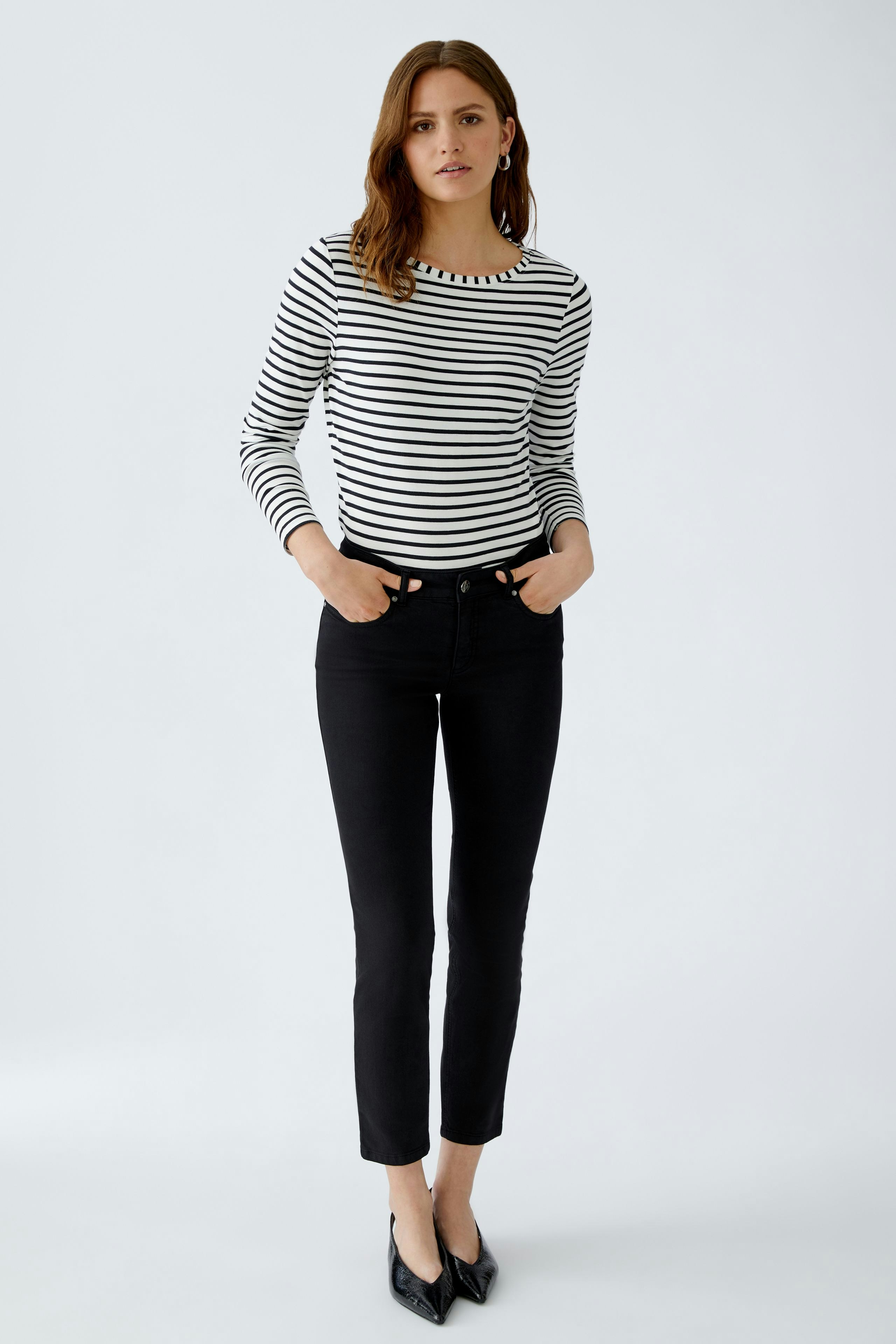 Langarmshirt: Junge Frau in gestreiftem Langarmshirt mit Rundhalsausschnitt und schwarzer Hose.