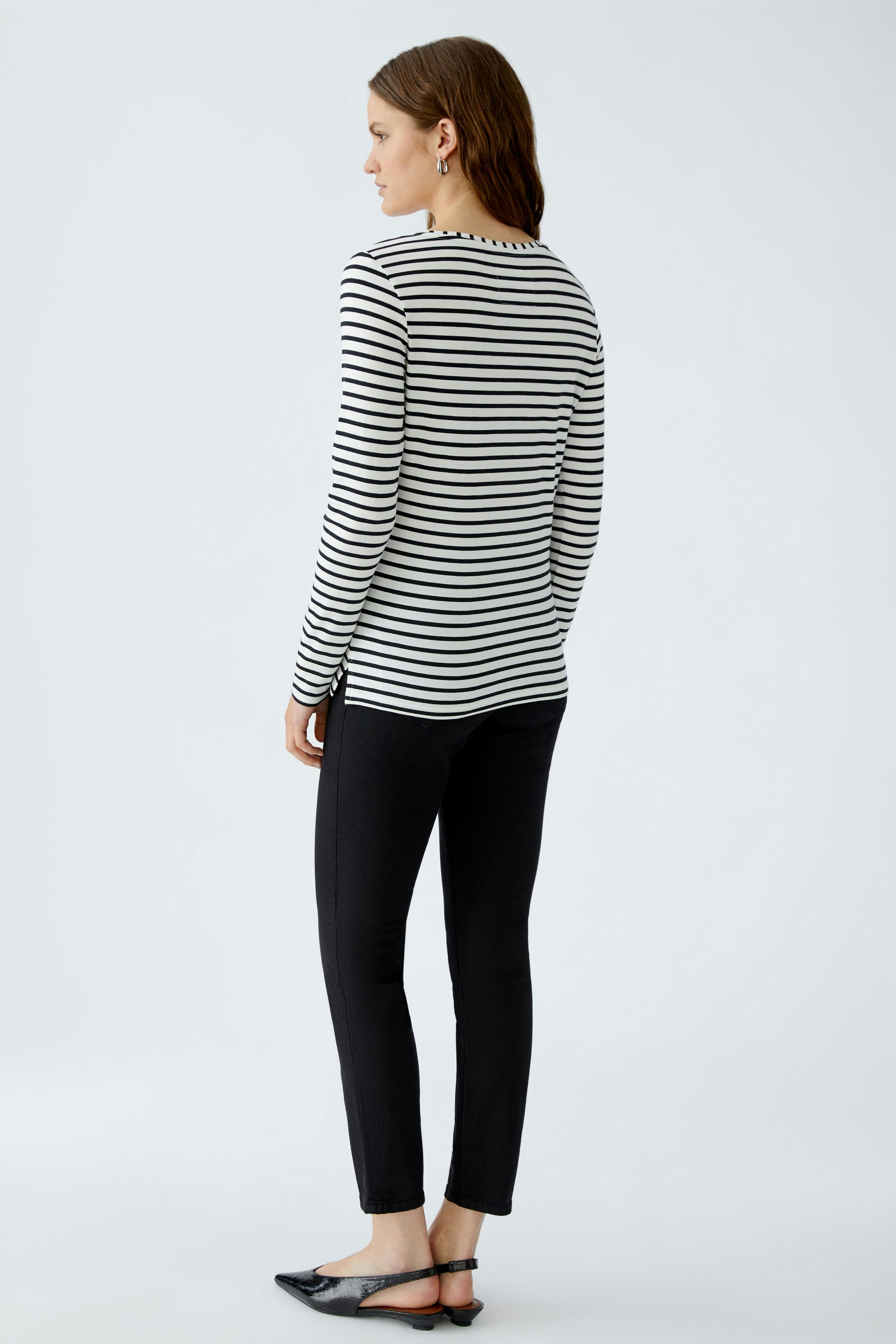 Damen Langarmshirt: Frau in gestreiftem Shirt mit langen Ärmeln und schmalen Hosen, lässiger Look.