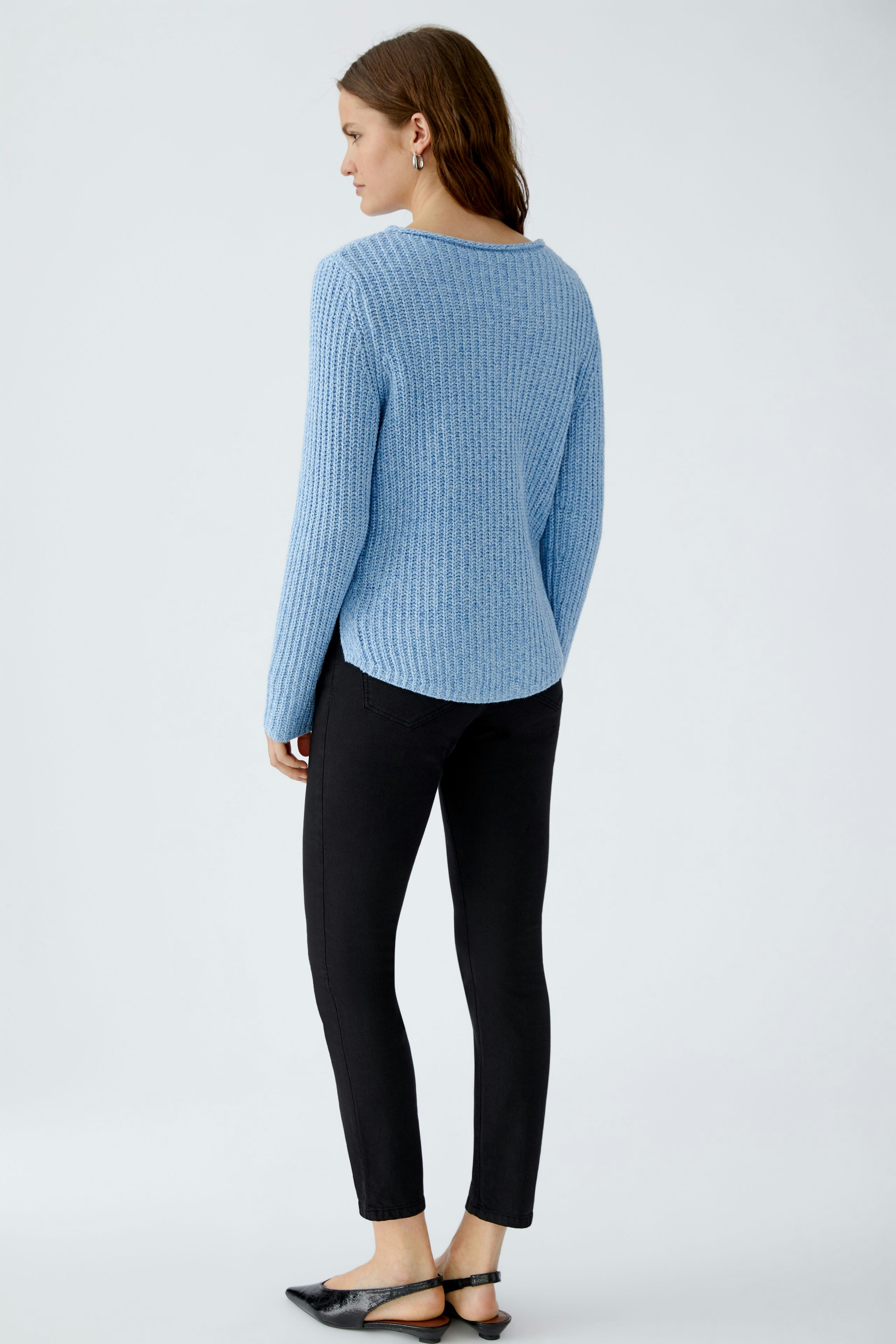 Stylish women's pullover: A woman in a light blue ribbed pullover paired with white pants.
