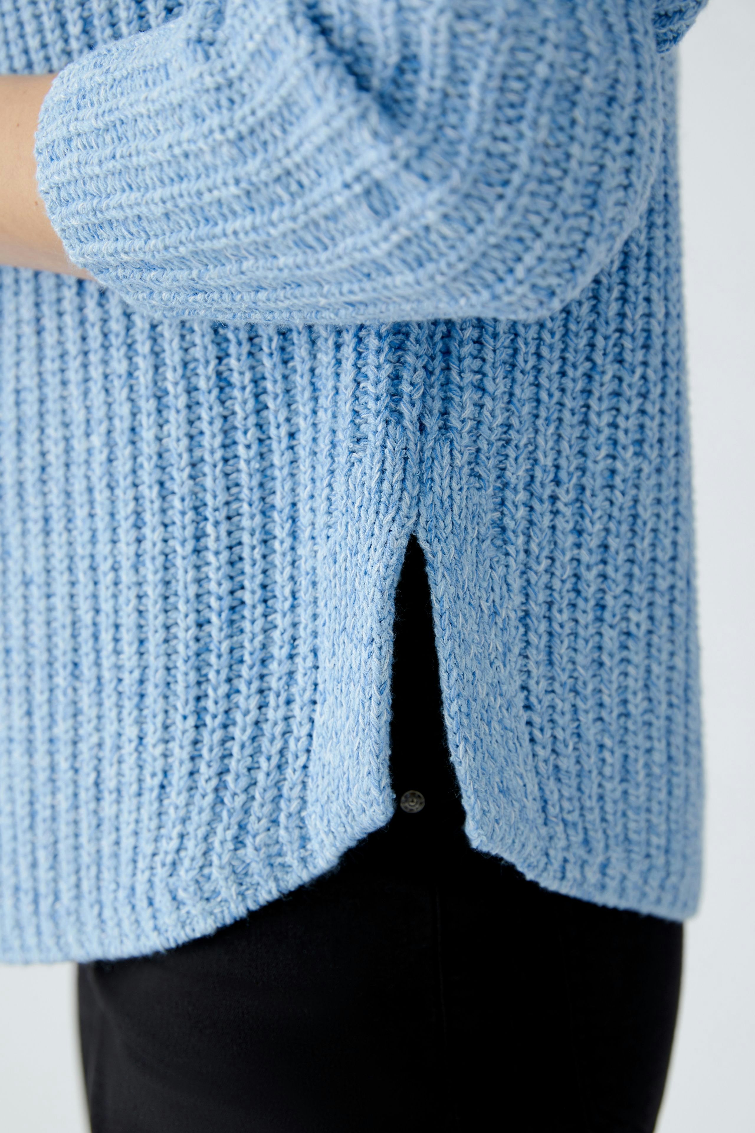 Modern women's pullover: A woman in a light blue textured pullover with a relaxed fit.