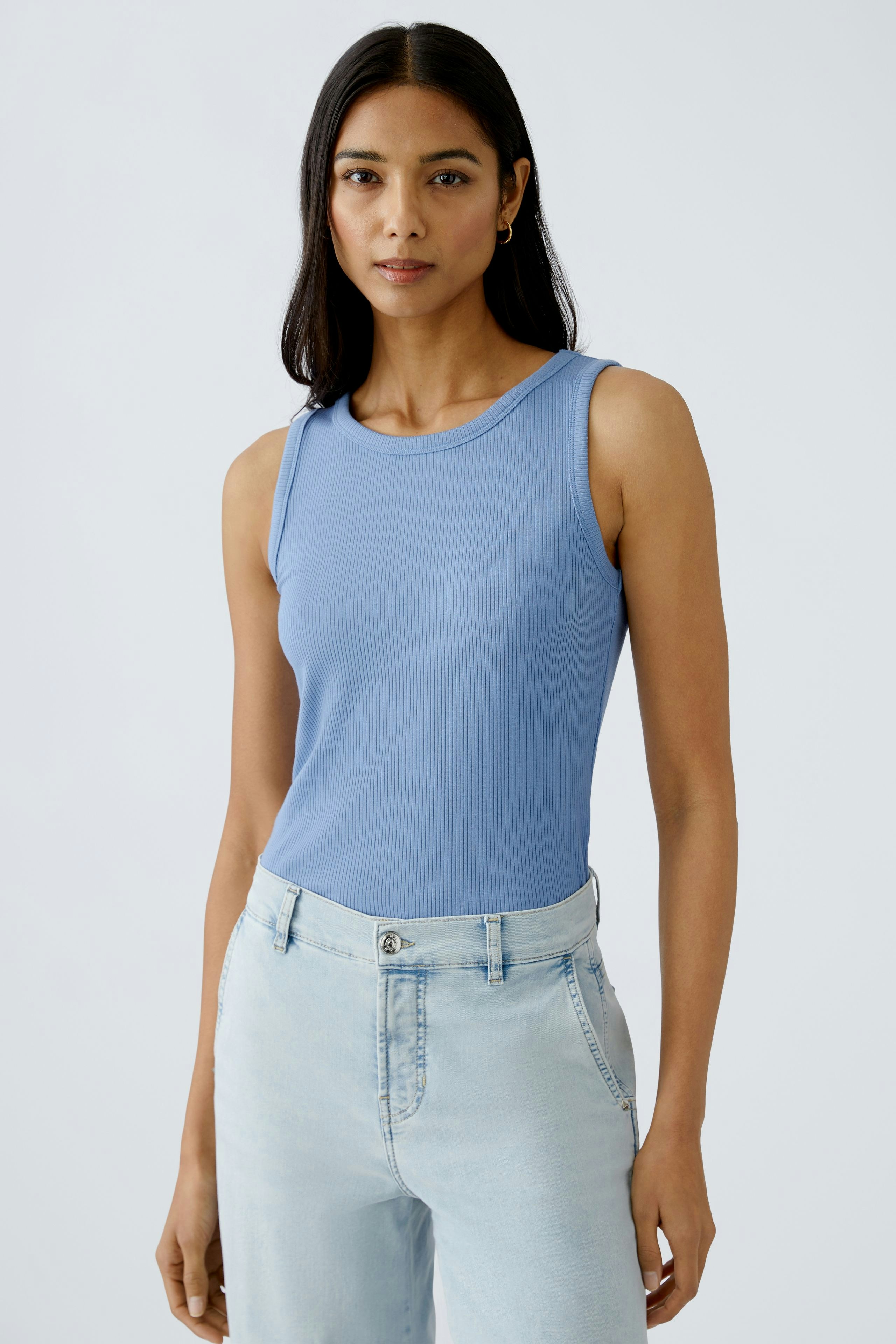 Stylish women's top: A woman in a light blue sleeveless top paired with light jeans.
