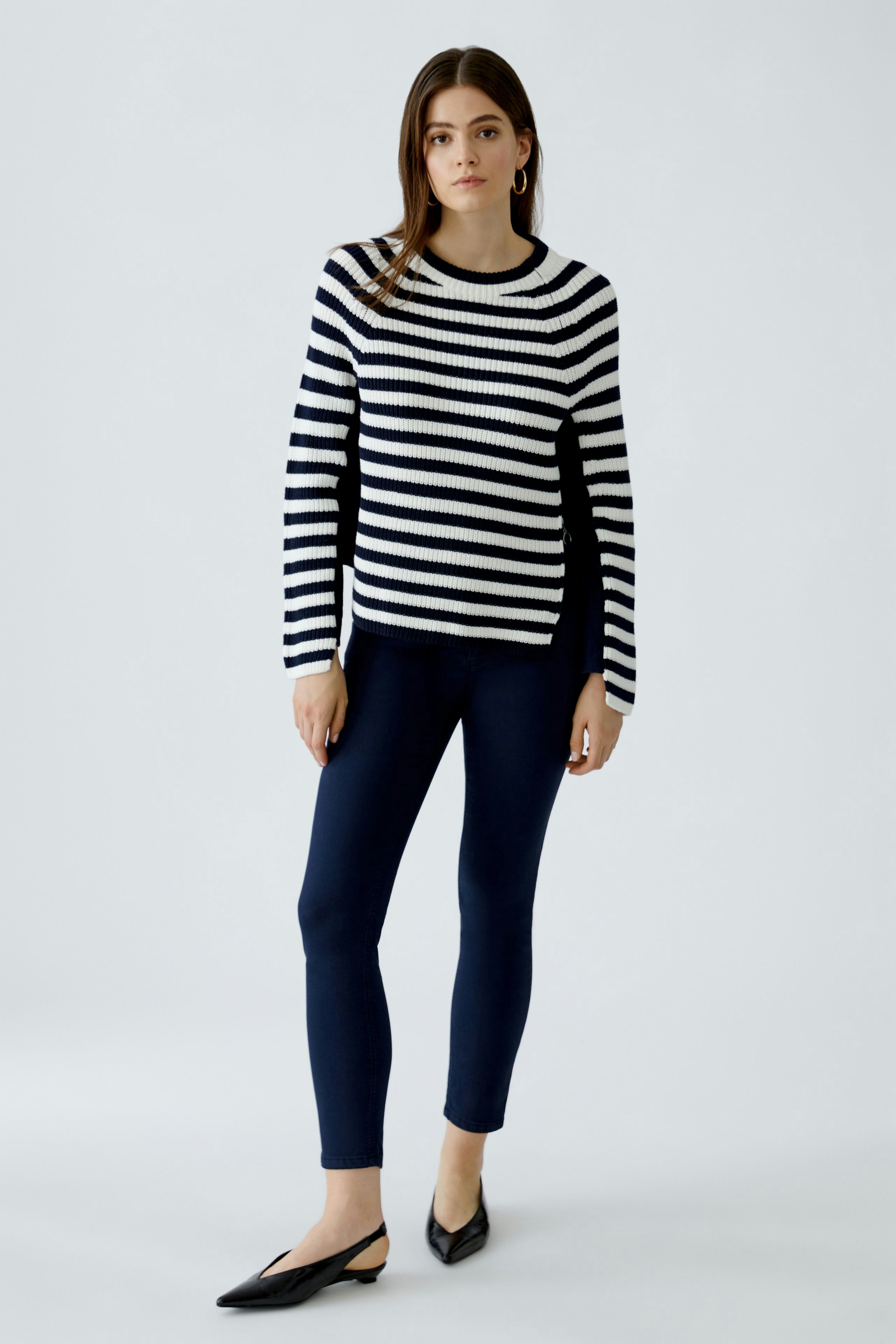 Damen-Pullover: Junge Frau im gestreiften Pullover in Schwarz und Weiß, kombiniert mit lässigen Jeans.