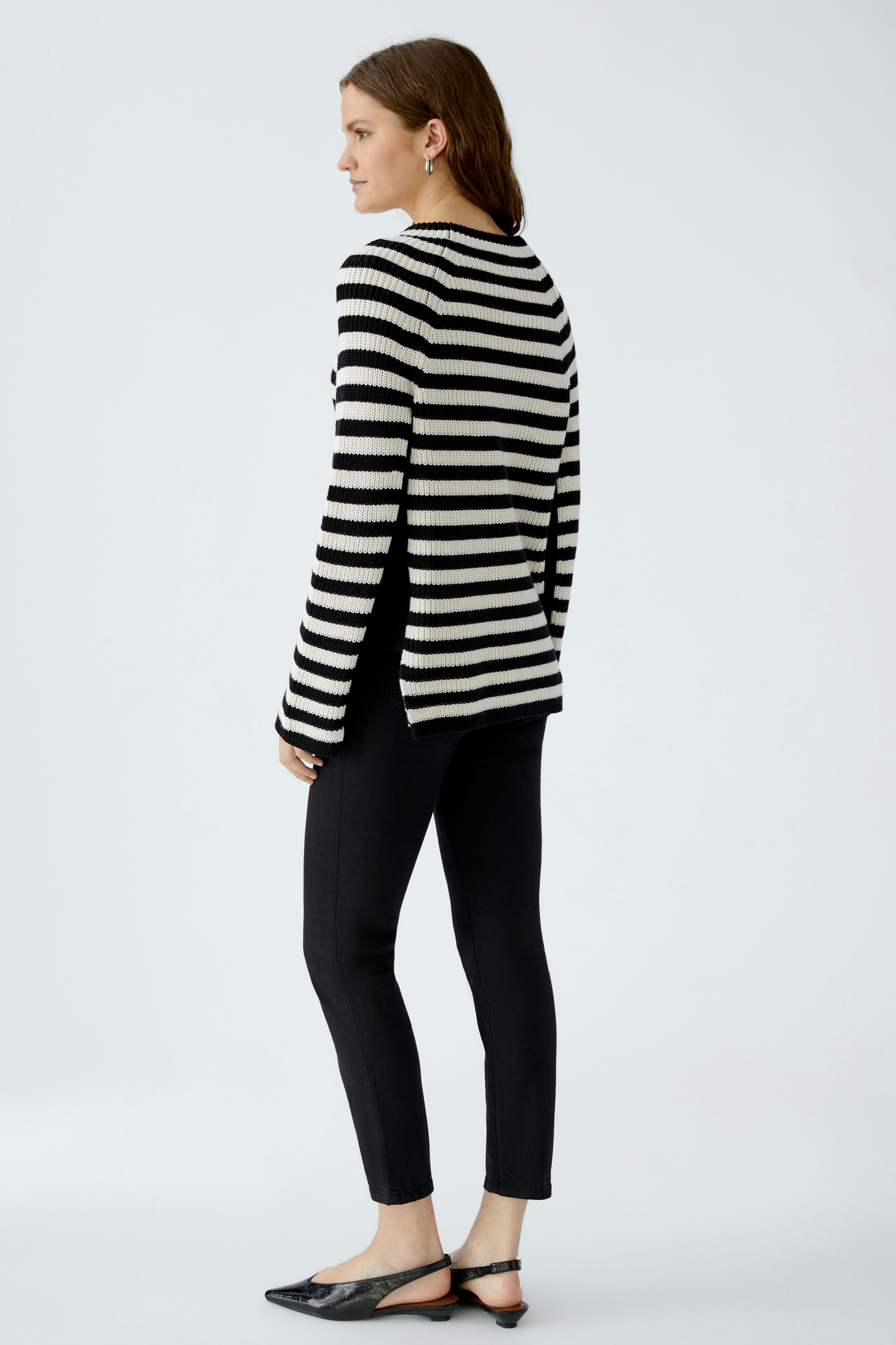 Stylish women's pullover: A woman in a striped black and white pullover, paired with sleek black pants.