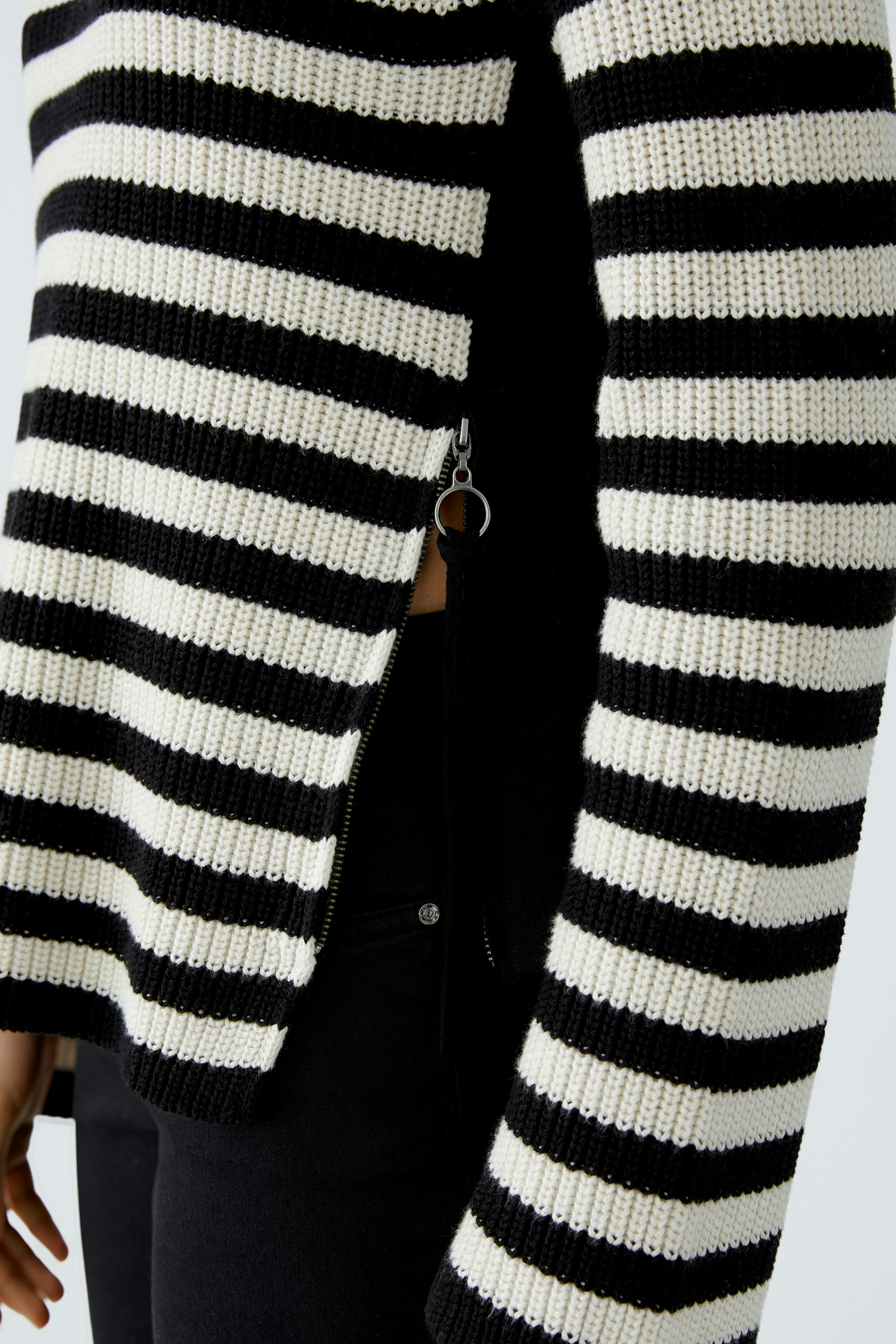 Modern women's pullover: A woman in a black and white striped pullover with a relaxed fit.