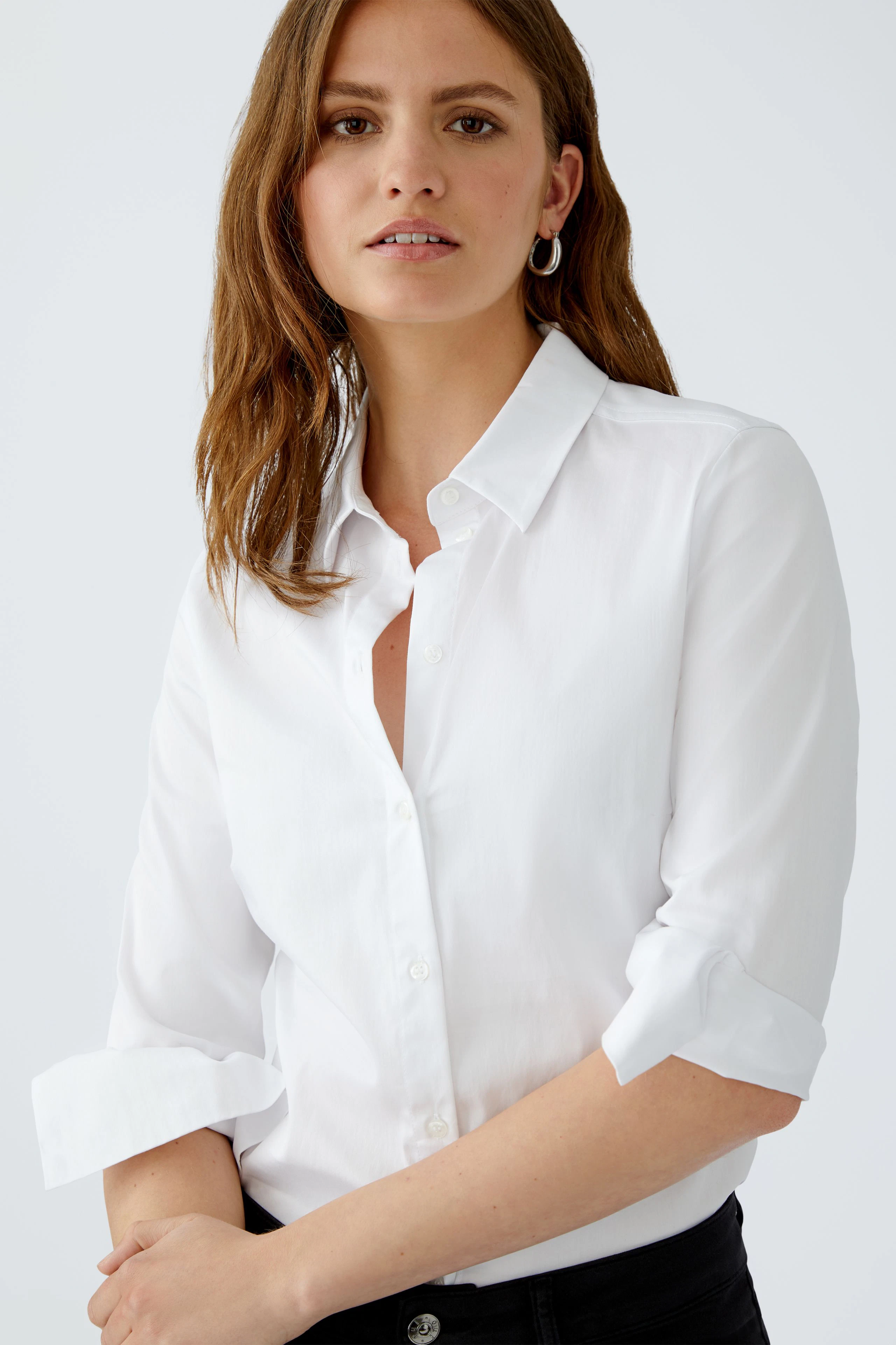 Elegante Damen-Bluse: Frau in weißer Bluse mit klassischem Kragen und lässigem Look.