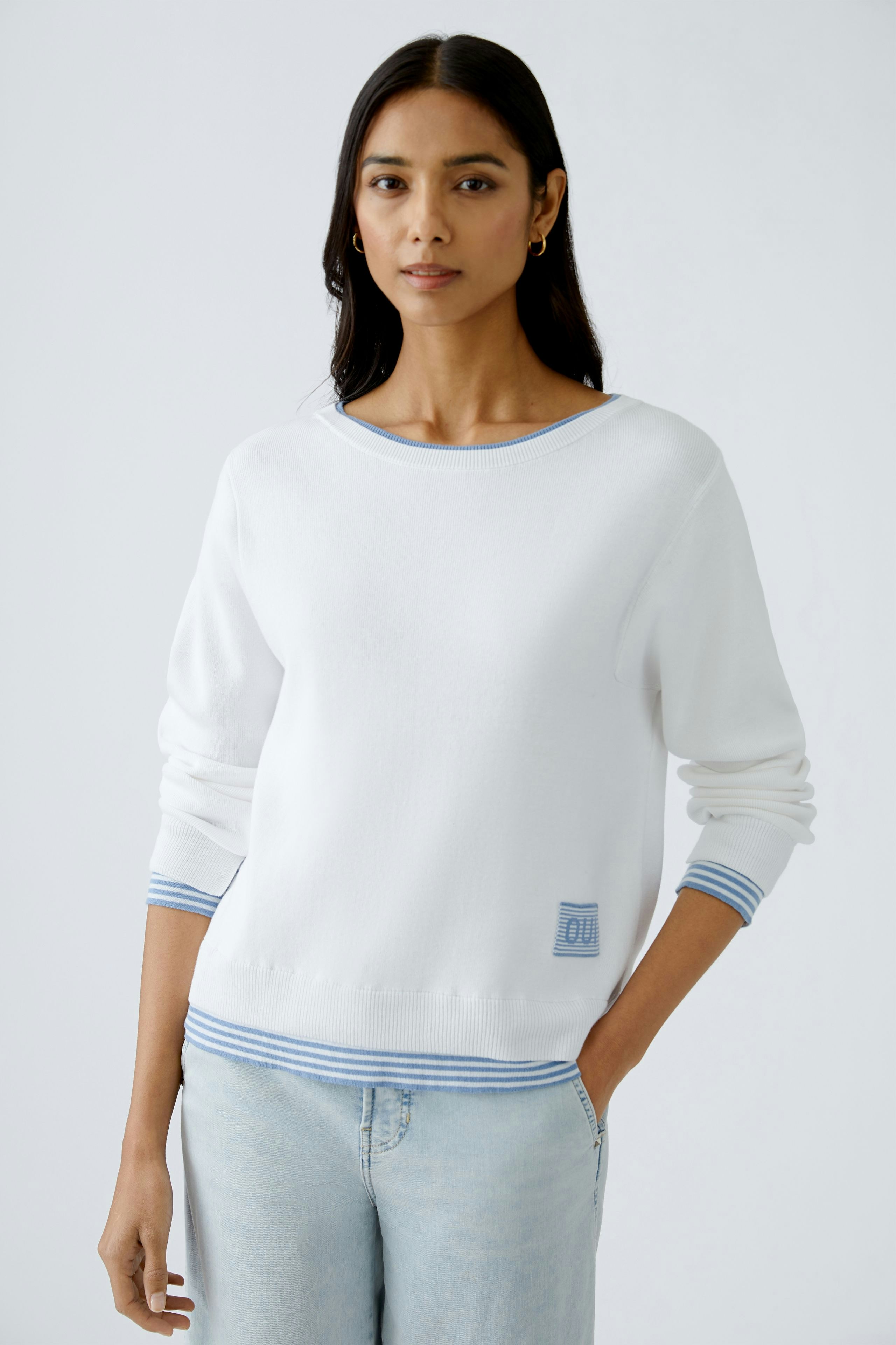 Stylish women's pullover: A woman in a white pullover with blue stripes, exuding casual elegance.