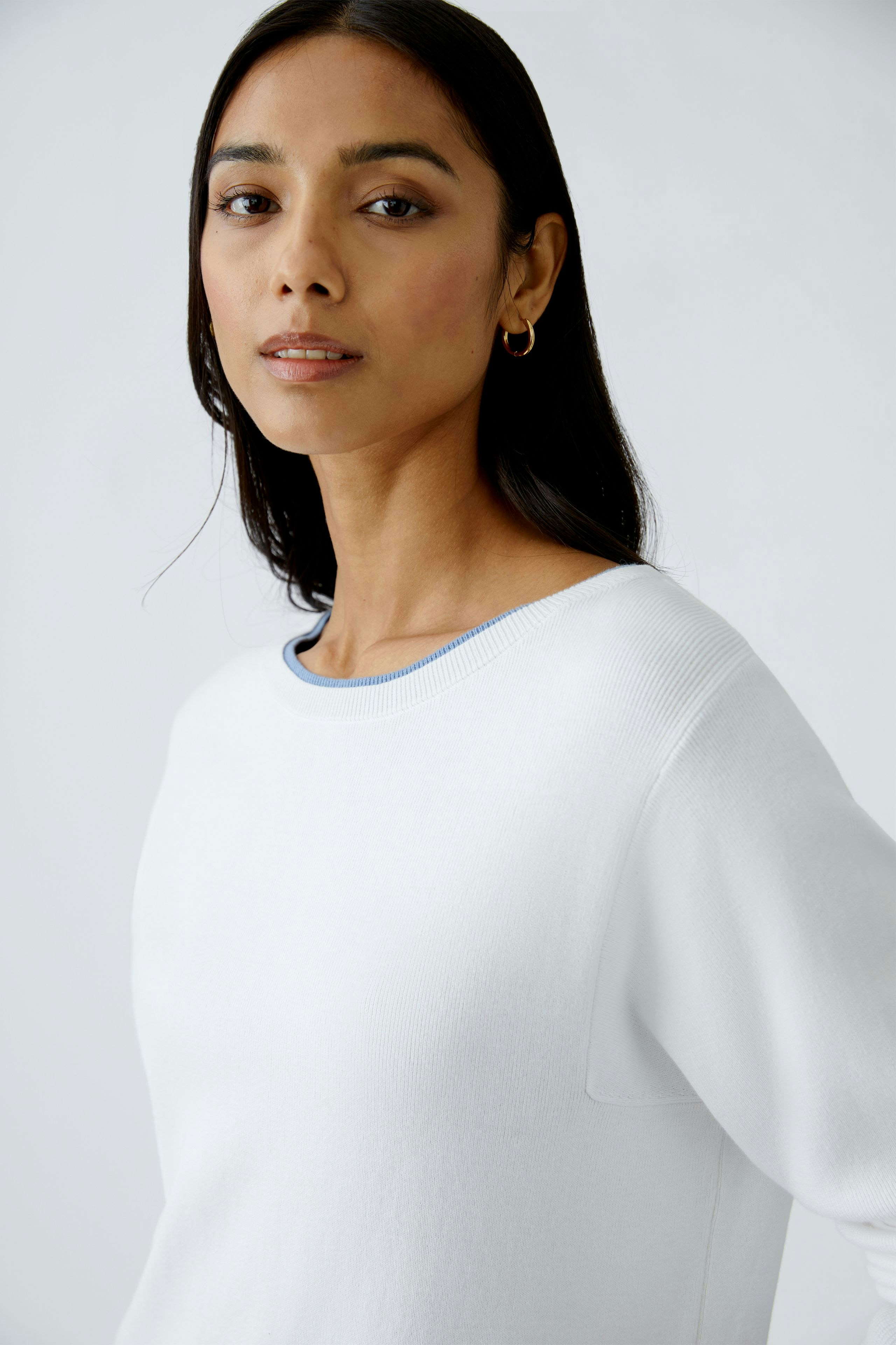 Modern women's pullover: A woman in a white pullover with a blue neckline, exuding effortless style.
