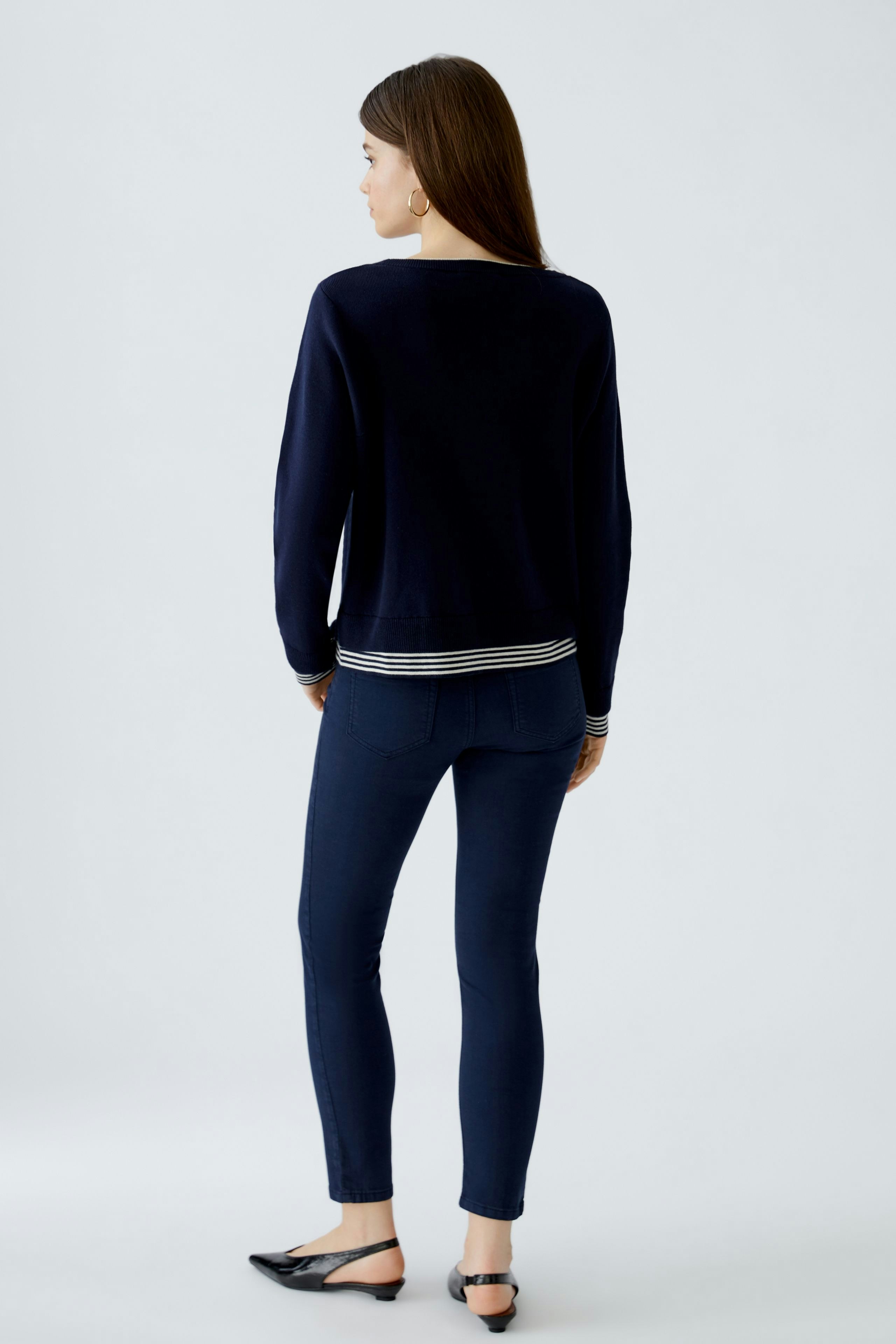 Stylish women's pullover: A woman in a navy pullover with striped hem, showcasing a relaxed fit.