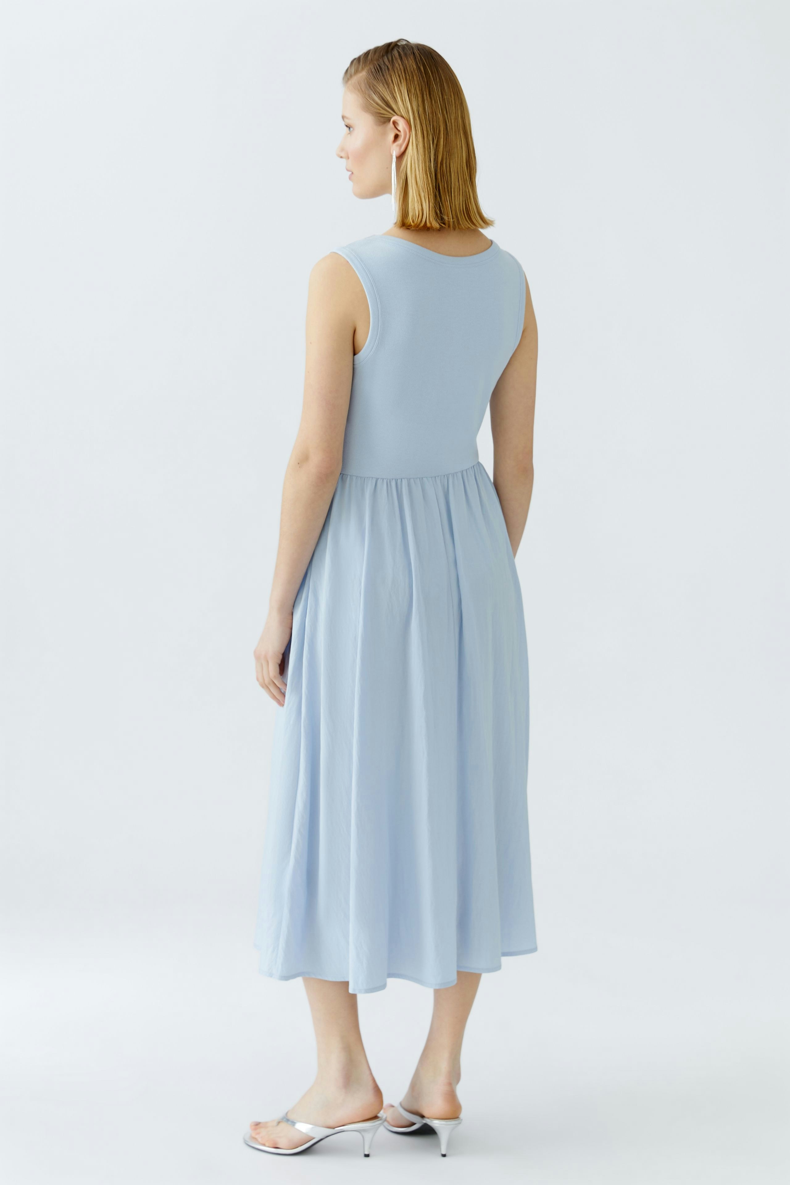 Damen-Kleid: Frau in einem hellblauen, ärmellosen Kleid mit fließendem Rock.