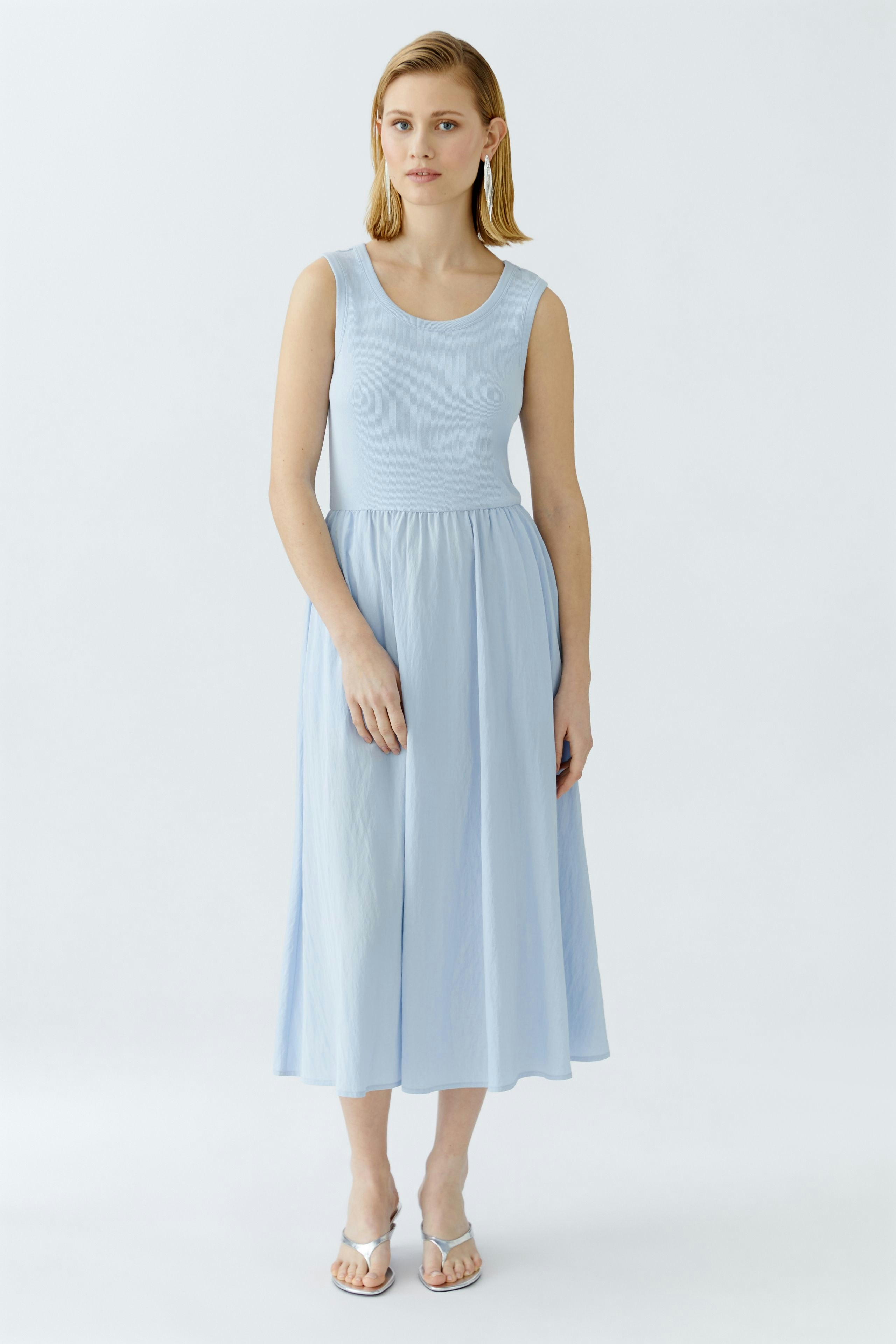 Elegantes Damen-Kleid: Frau in einem hellblauen, ärmellosen Kleid mit fließendem Rock.
