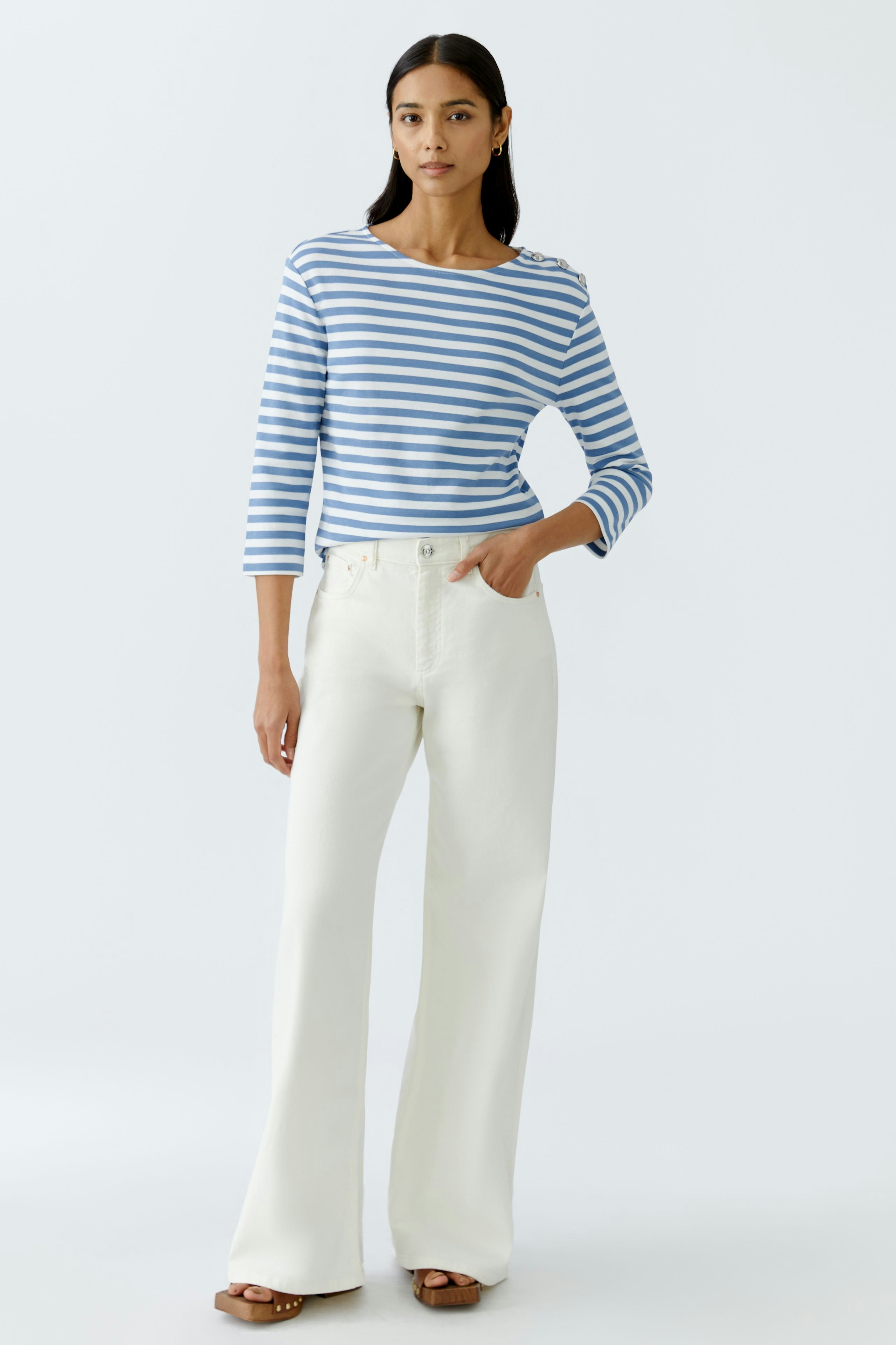 Stylish long-sleeve shirt: Woman in a blue and white striped pullover paired with white wide-leg pants.