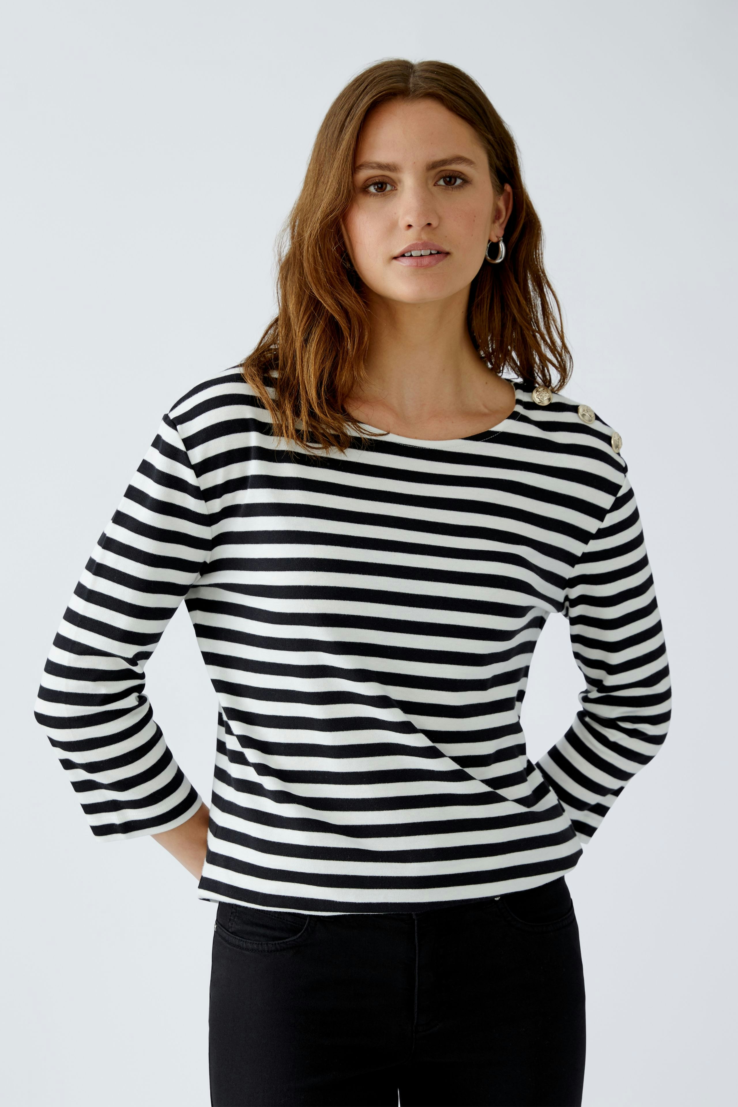 Stylish long-sleeve shirt: Woman in a black and white striped pullover with button details.