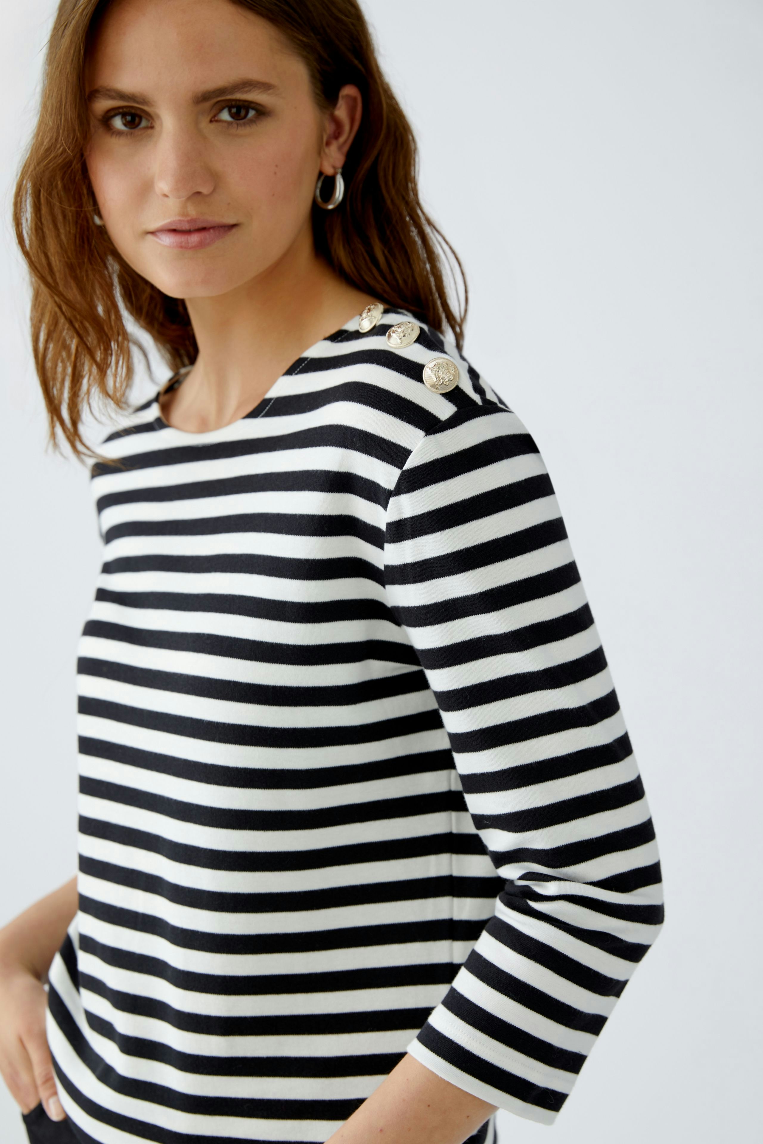 Stylish women's long-sleeve shirt: A woman in a black and white striped pullover with button details.