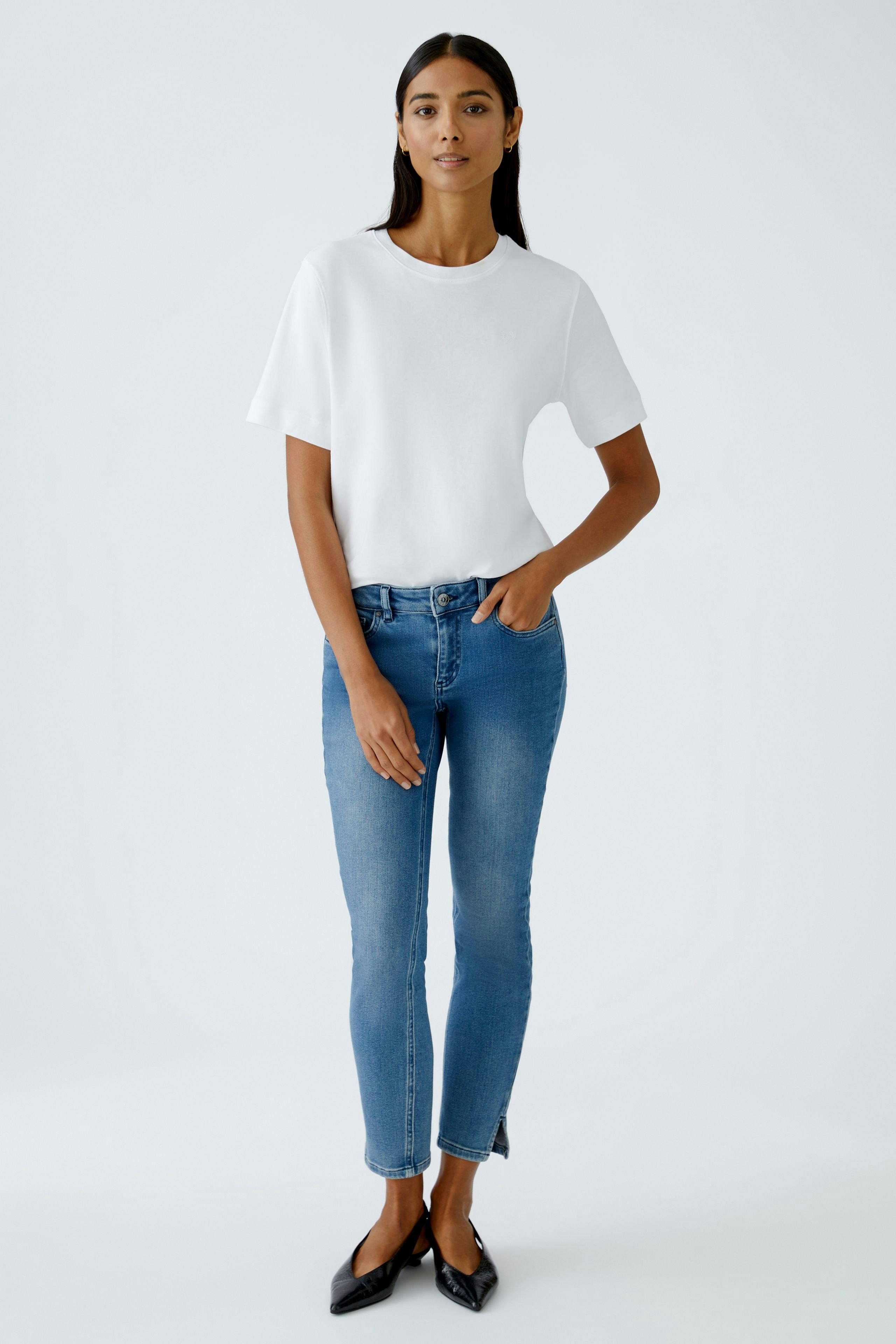 Casual women's T-shirt: A woman in a white T-shirt paired with blue jeans stands confidently.