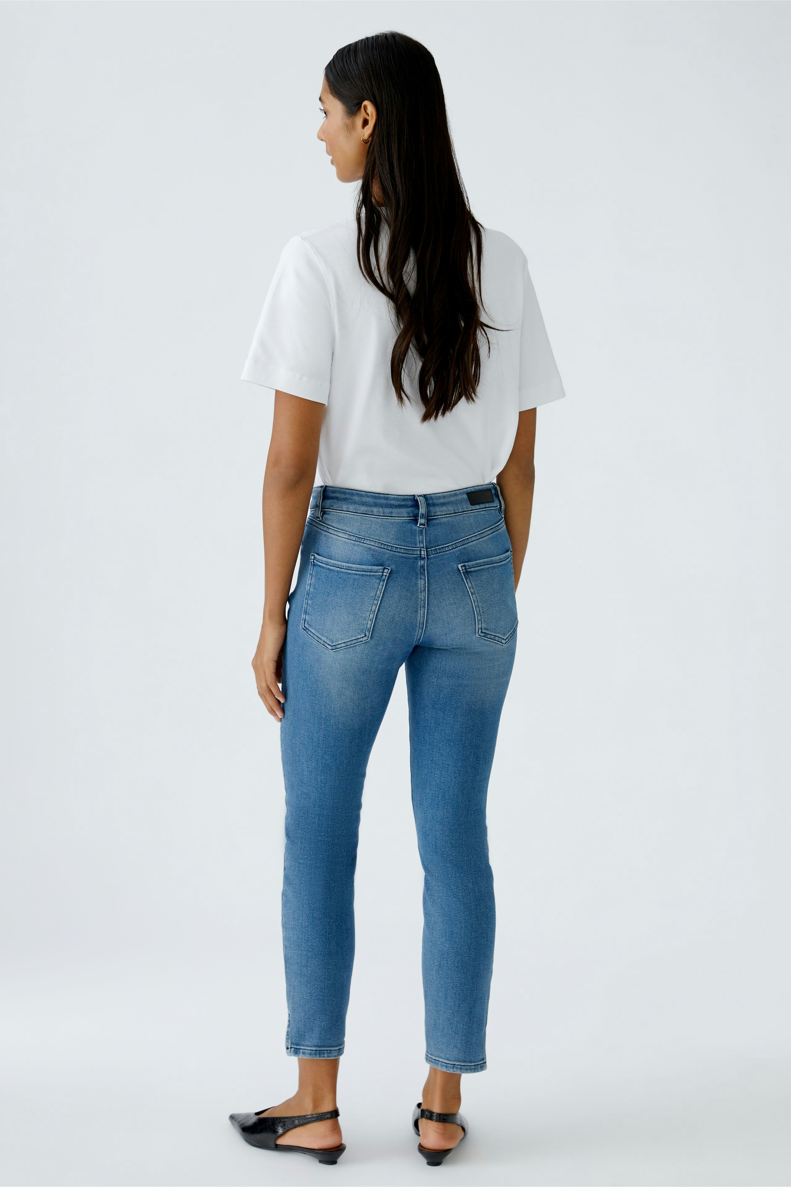 Casual women's T-shirt: Woman in a white tee paired with blue jeans, showcasing a relaxed style.