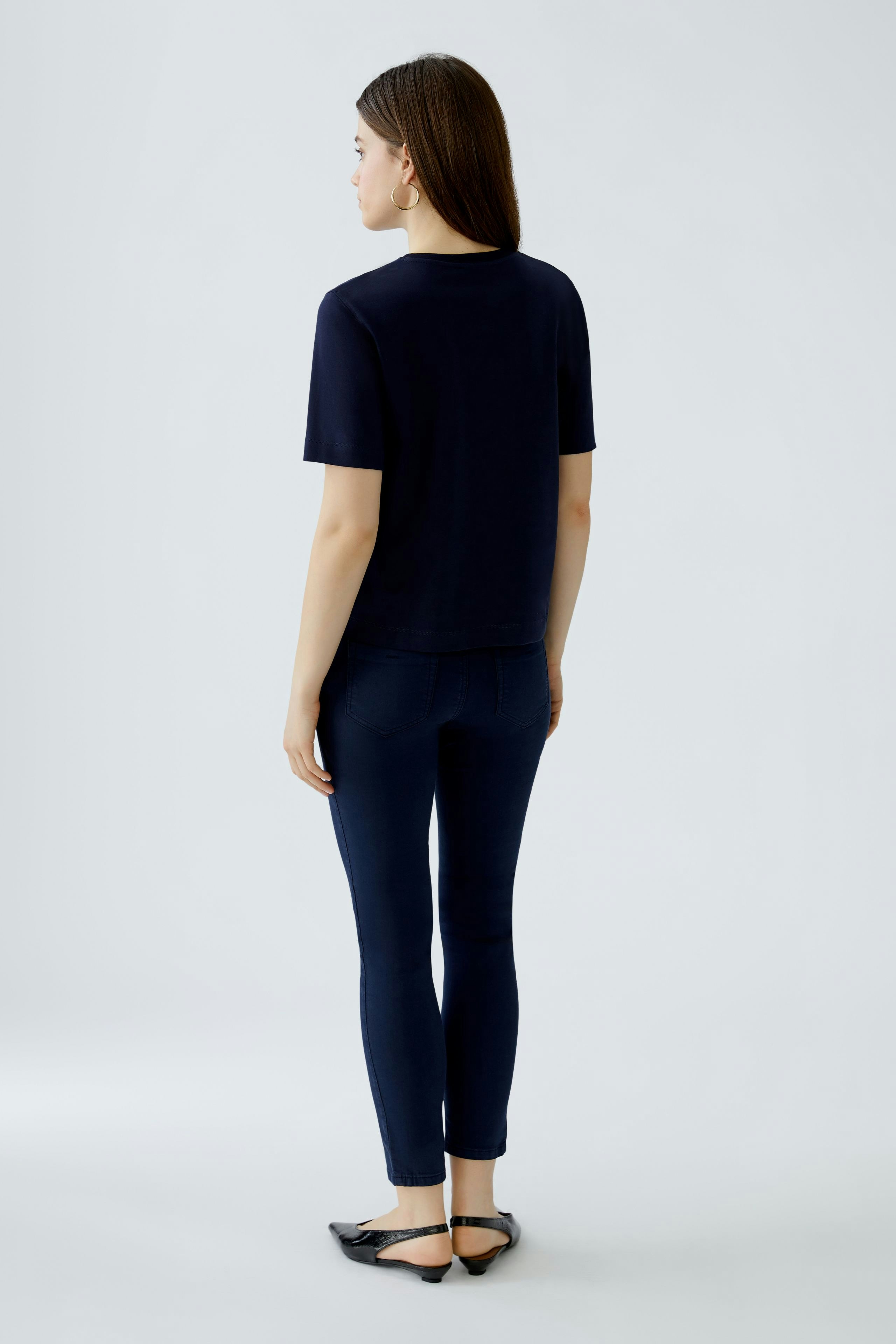 Damen-T-Shirt: Frau in navyblauem T-Shirt und Jeans von hinten.