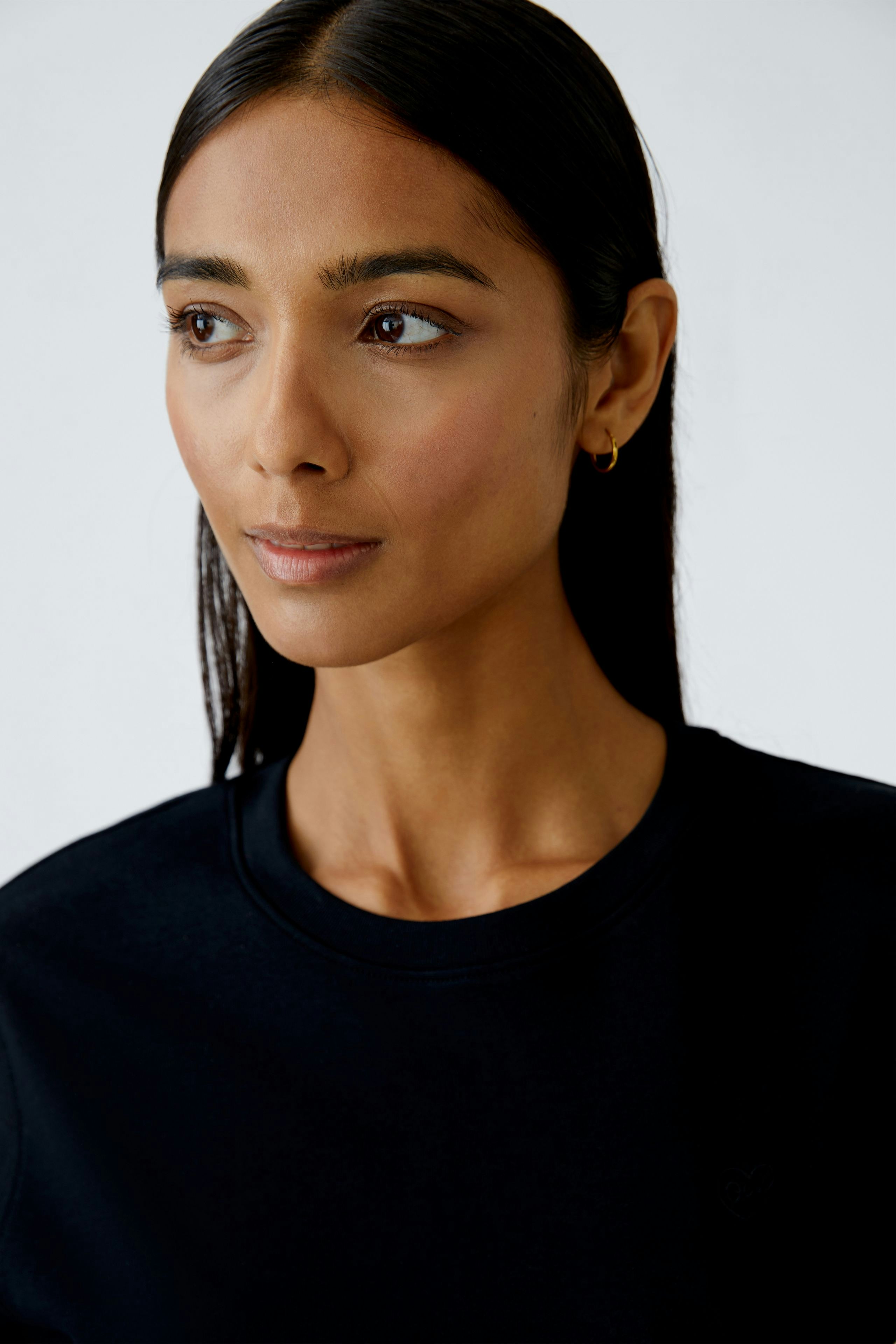 Schwarzes Damen-T-Shirt: Frau mit schlichtem Design und Rundhalsausschnitt, ideal für den Alltag.