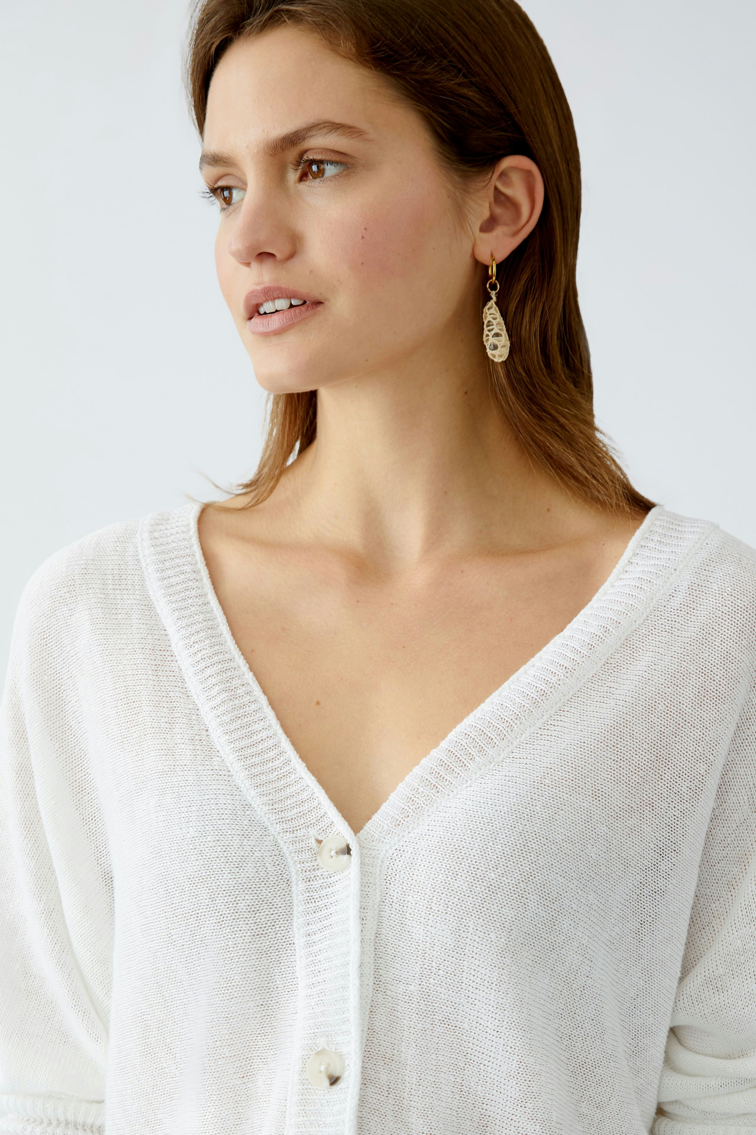 Stylish women's cardigan: A woman in a white cardigan with a deep V-neck and buttons, exuding elegance.