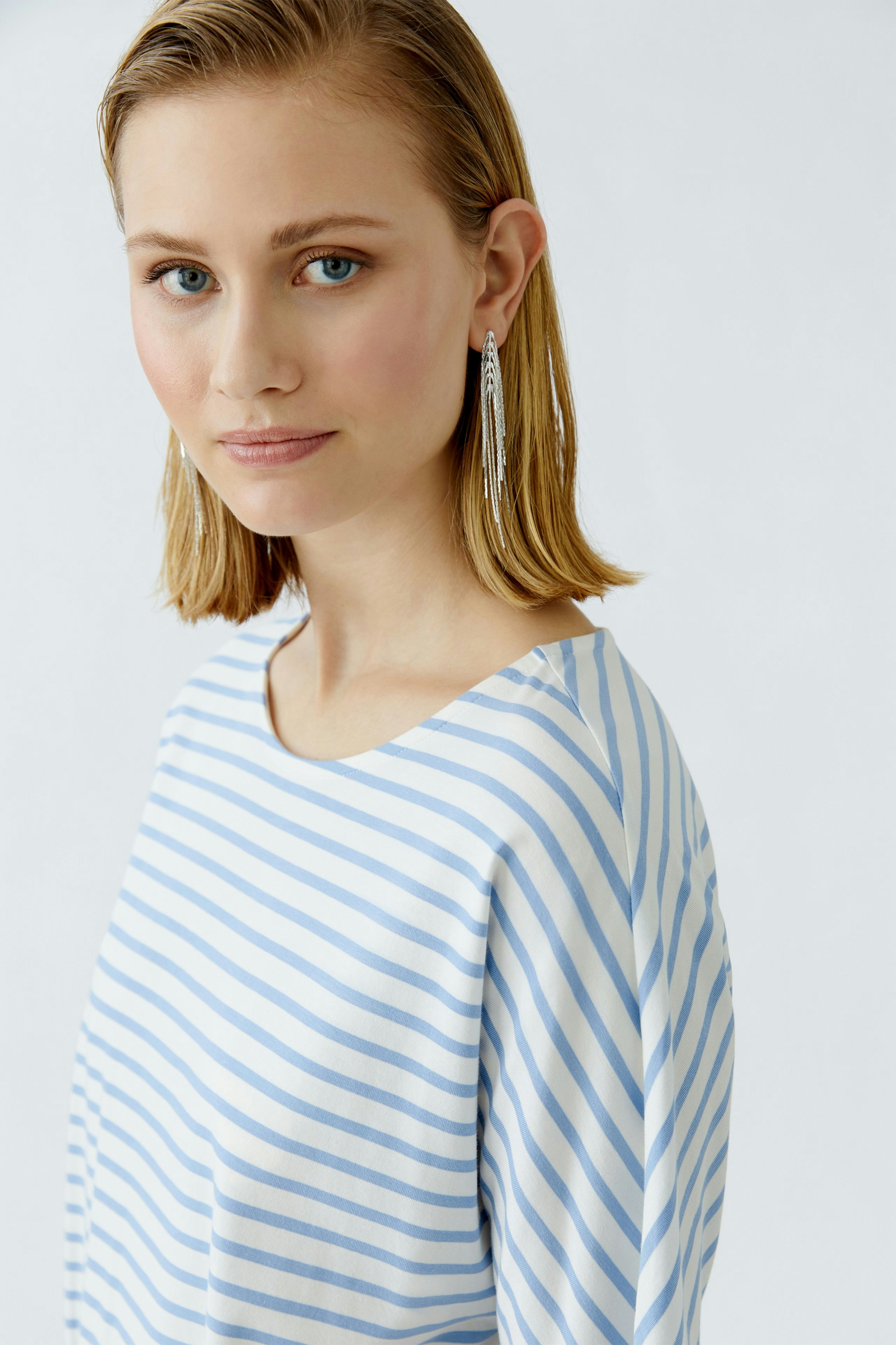 Casual women's T-shirt: Young woman in a striped blue and white top, showcasing a relaxed style.